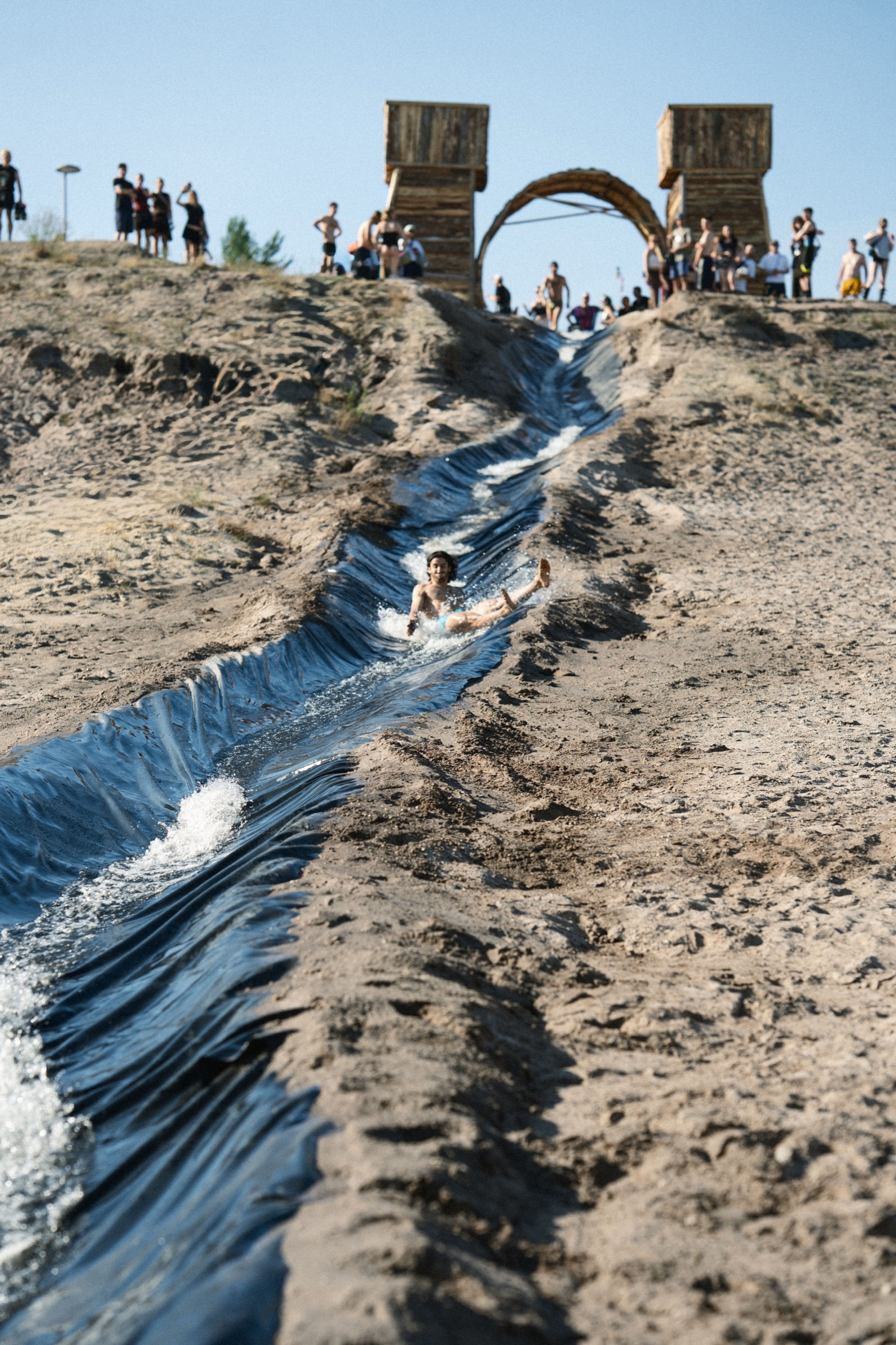 Someone sliding down a sand water-slide toward the crowd