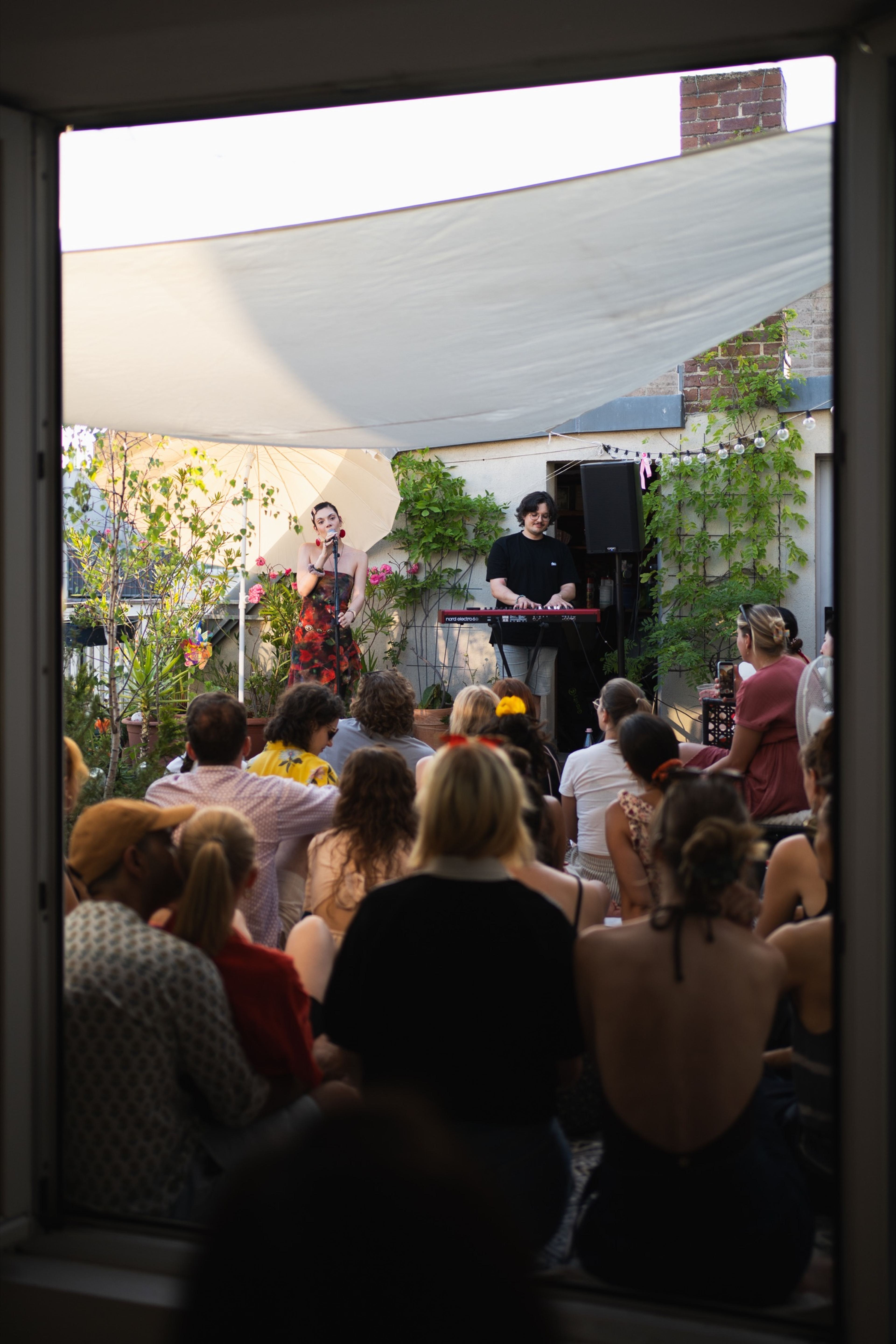 View through a doorway of the audience watching the performers at a Her Sound rooftop concert