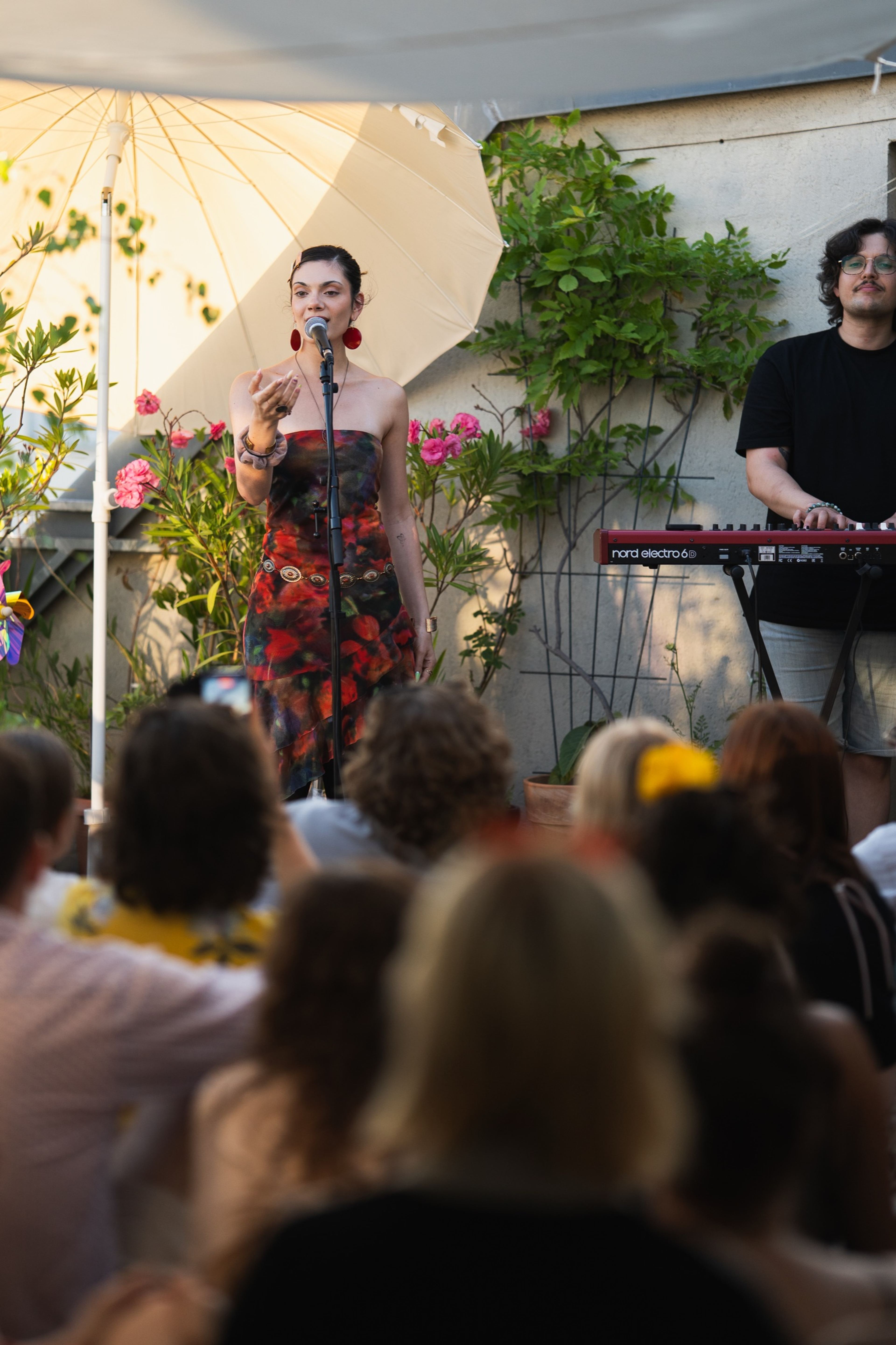 Vocalist in a floral dress performing to the seated crowd