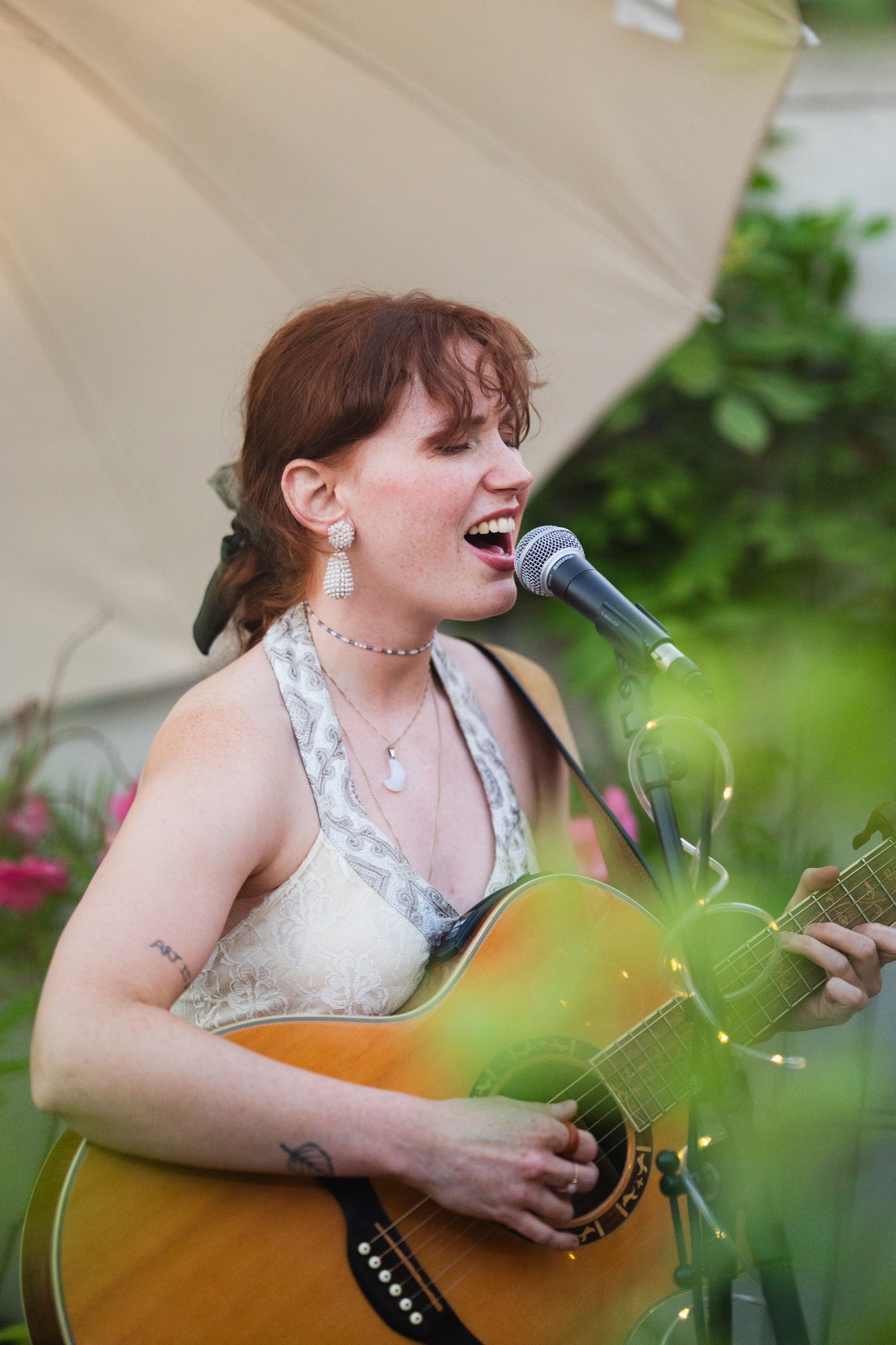 Singer-songwriter performing with an acoustic guitar among the rooftop plants