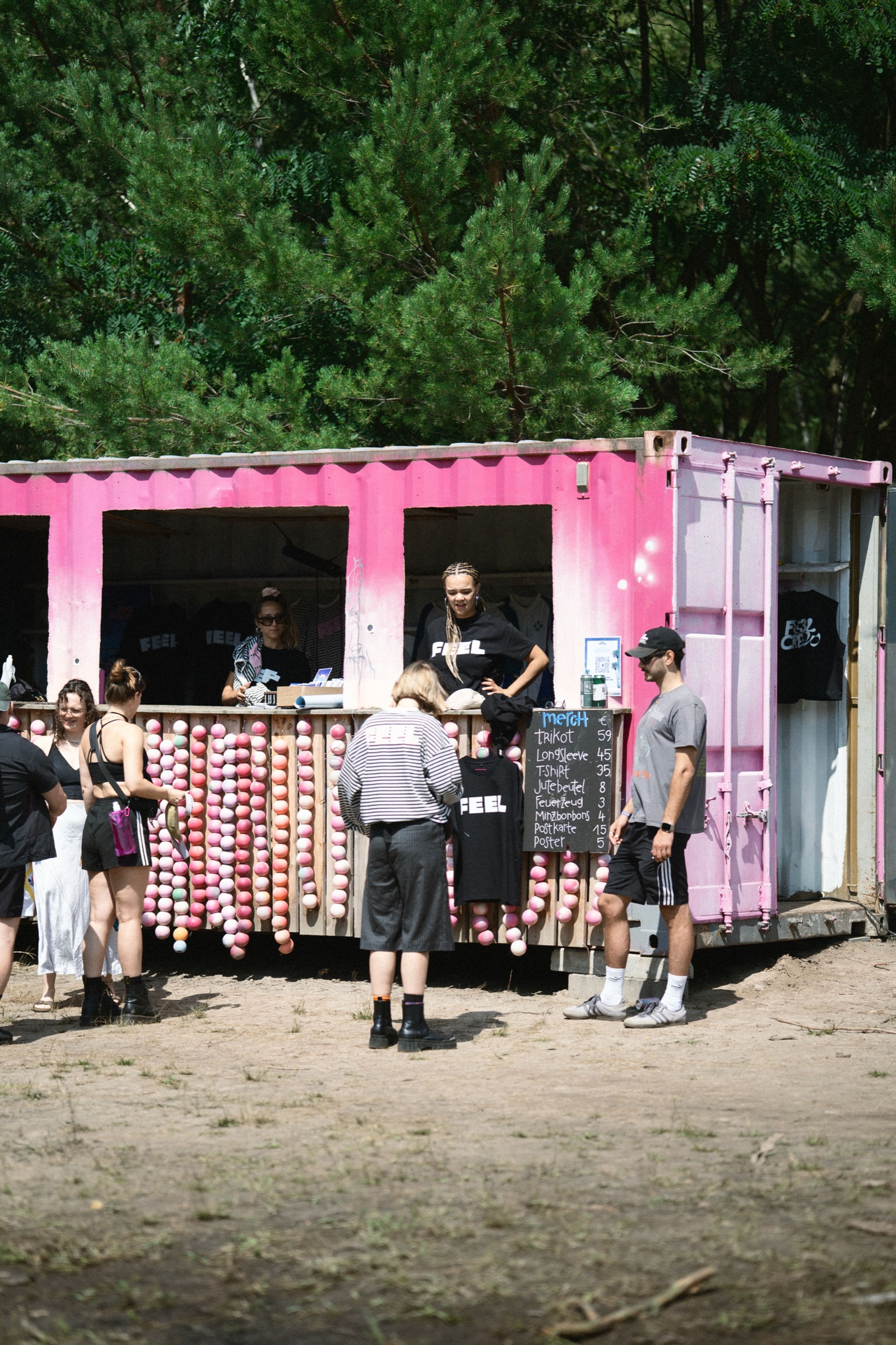 The pink FEEL merch stand built into a shipping container in the woods