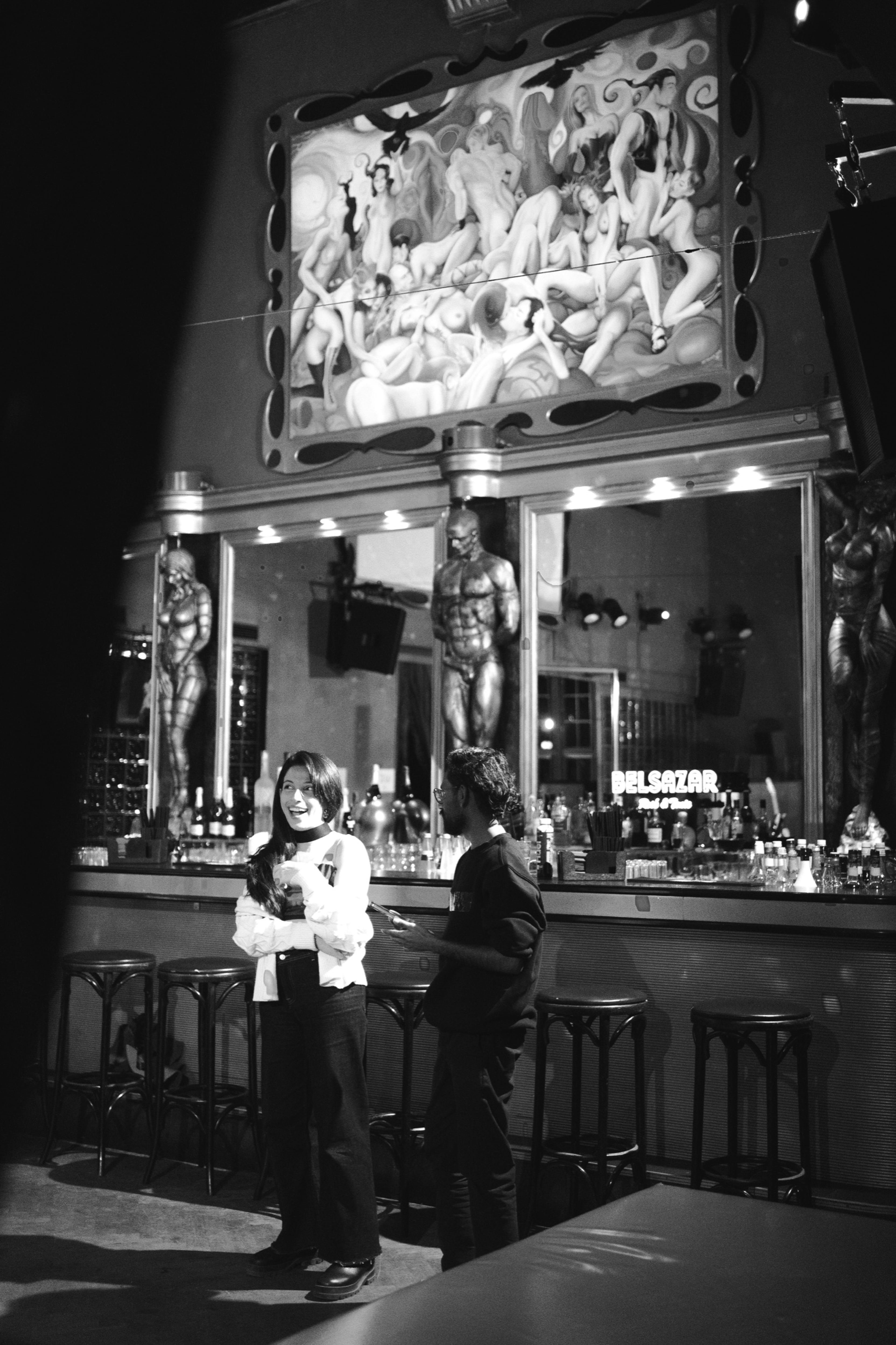 Two guests by the ornate bar before the show, in black and white