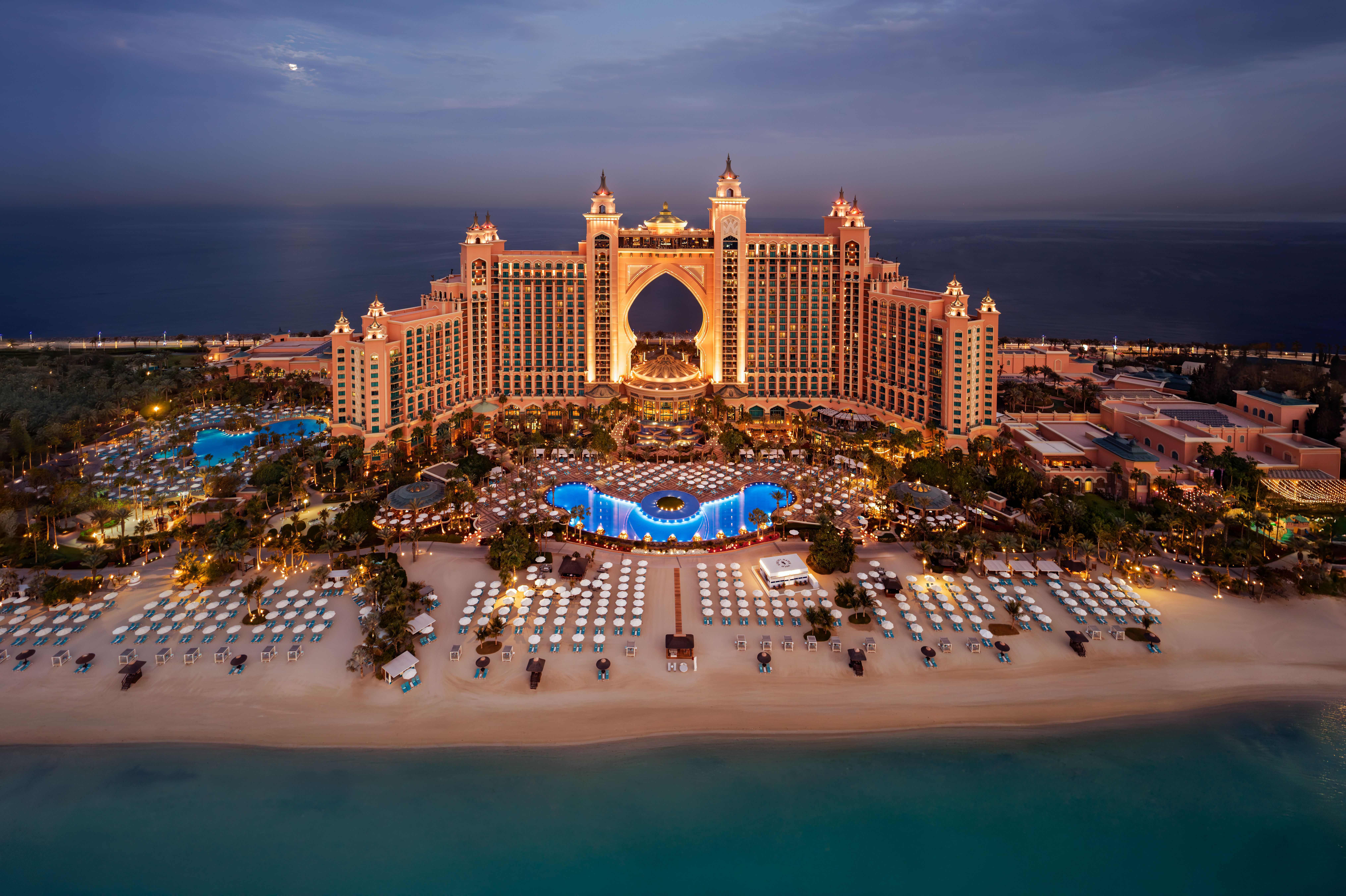 Atlantis The Palm lit up at dusk above its beach
