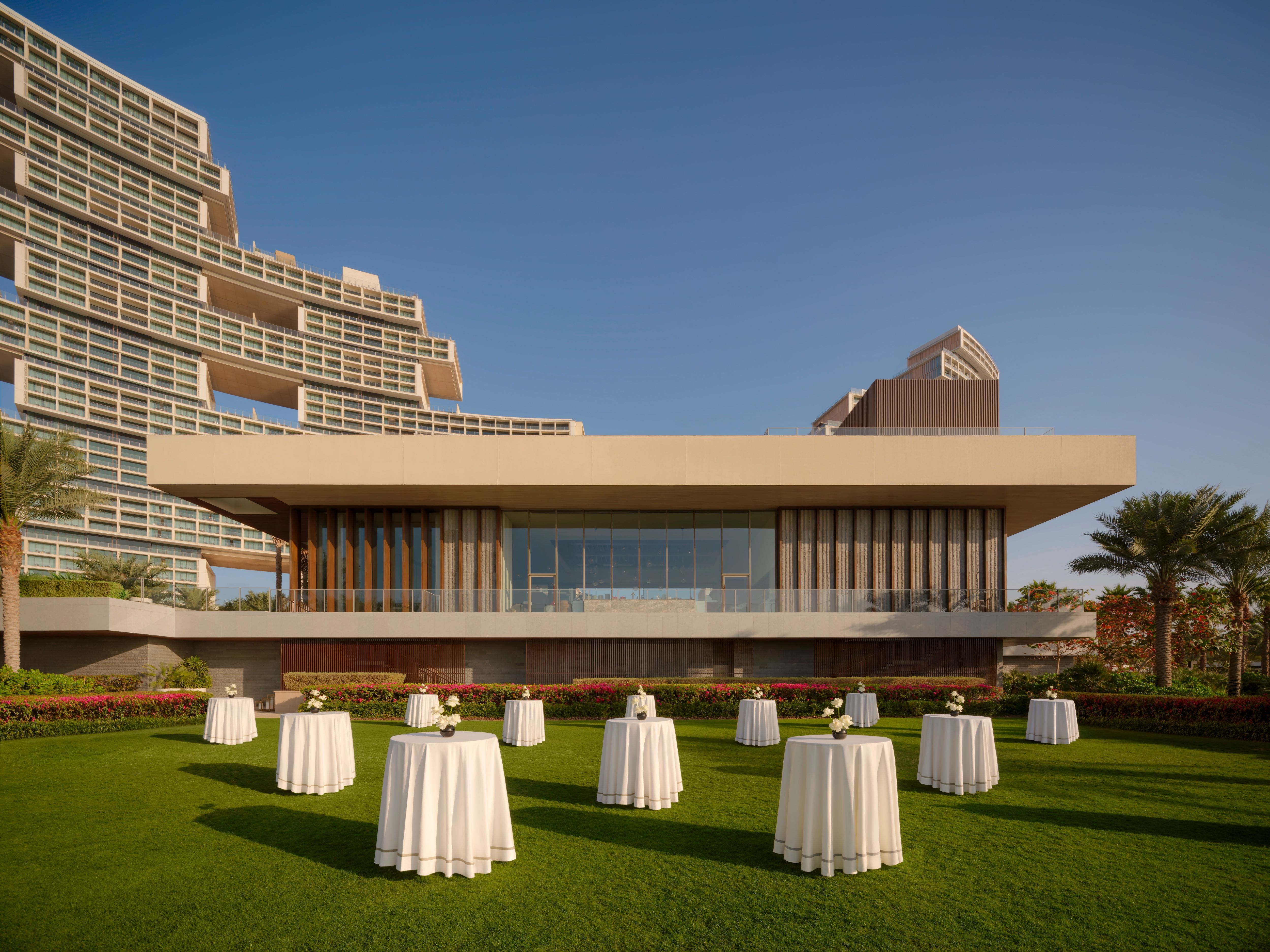 Cocktail tables dressed in white on the lawn beside Estiatorio Milos at Atlantis The Royal