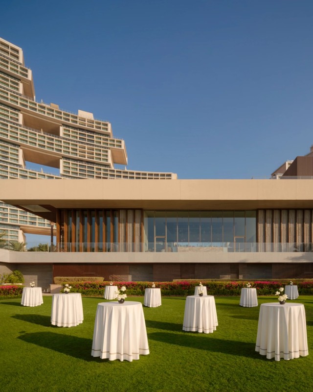 Cocktail tables dressed in white on the lawn beside Estiatorio Milos at Atlantis The Royal