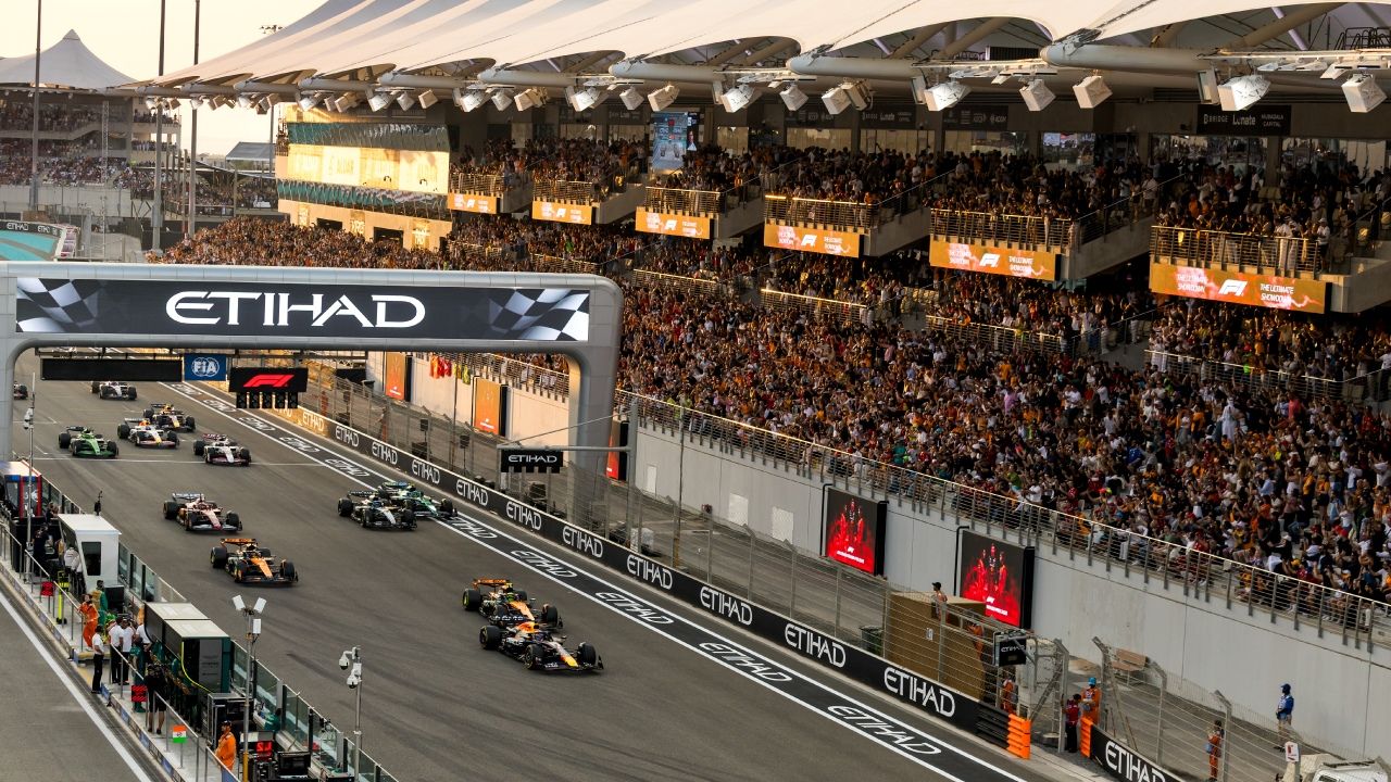 Cars streaming under the Etihad gantry past a packed grandstand at the Abu Dhabi Grand Prix