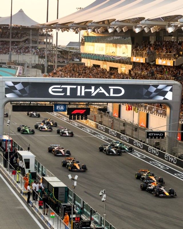 Cars streaming under the Etihad gantry past a packed grandstand at the Abu Dhabi Grand Prix