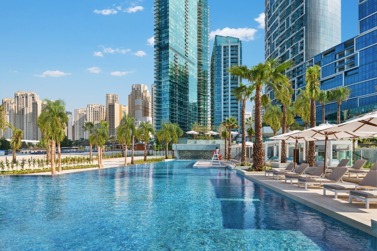 Address Beach Resort pool deck with palms and loungers below the Dubai Marina towers