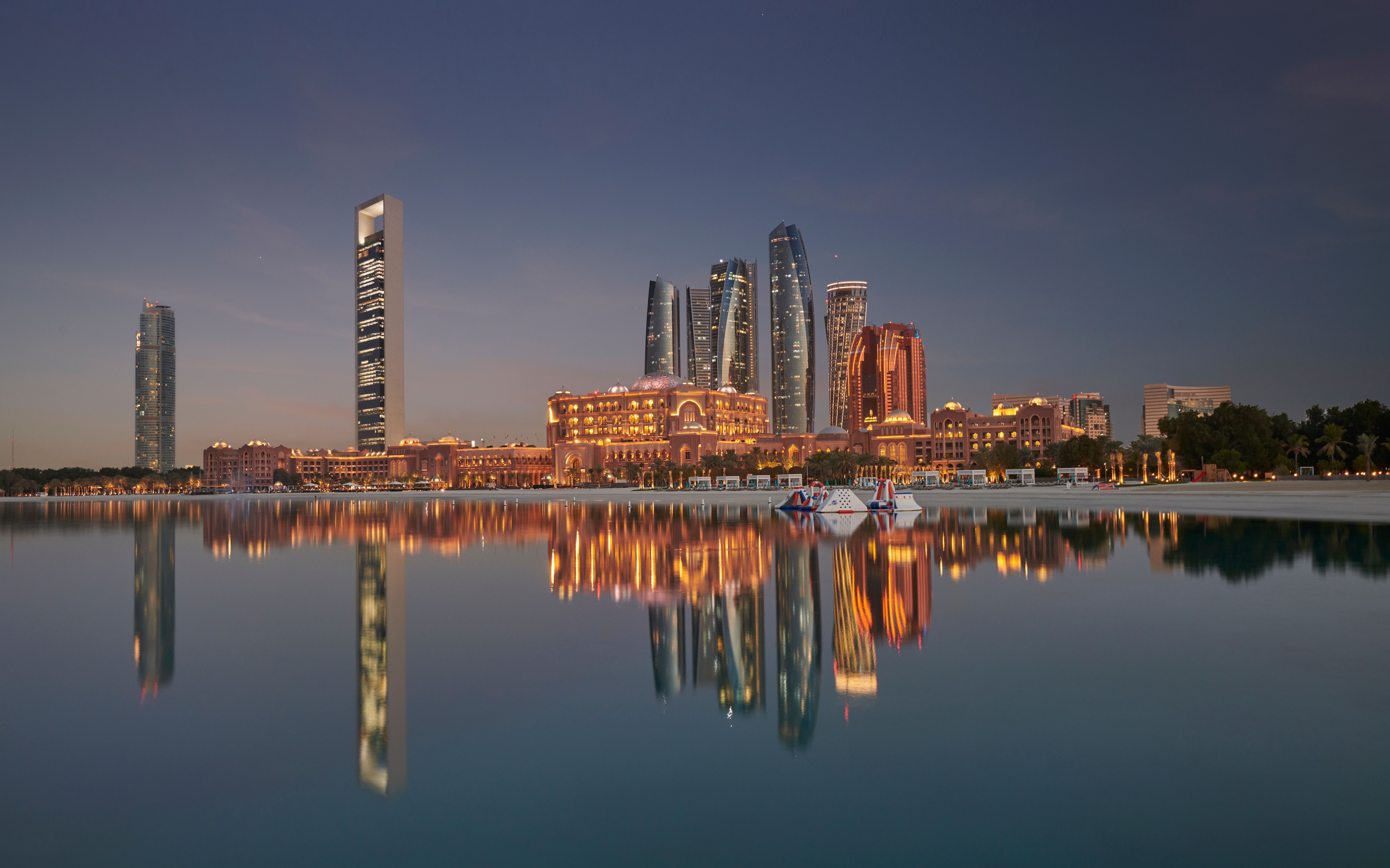 Abu Dhabi's skyline at dusk, reflected in the still water of the Gulf