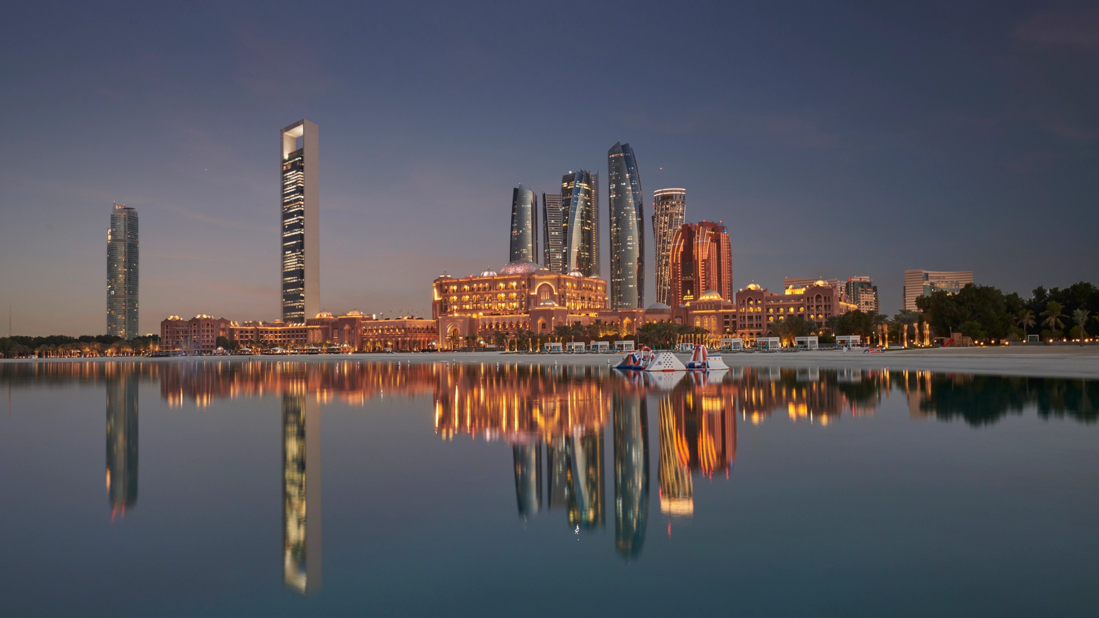 The Abu Dhabi skyline at night, reflected in the water