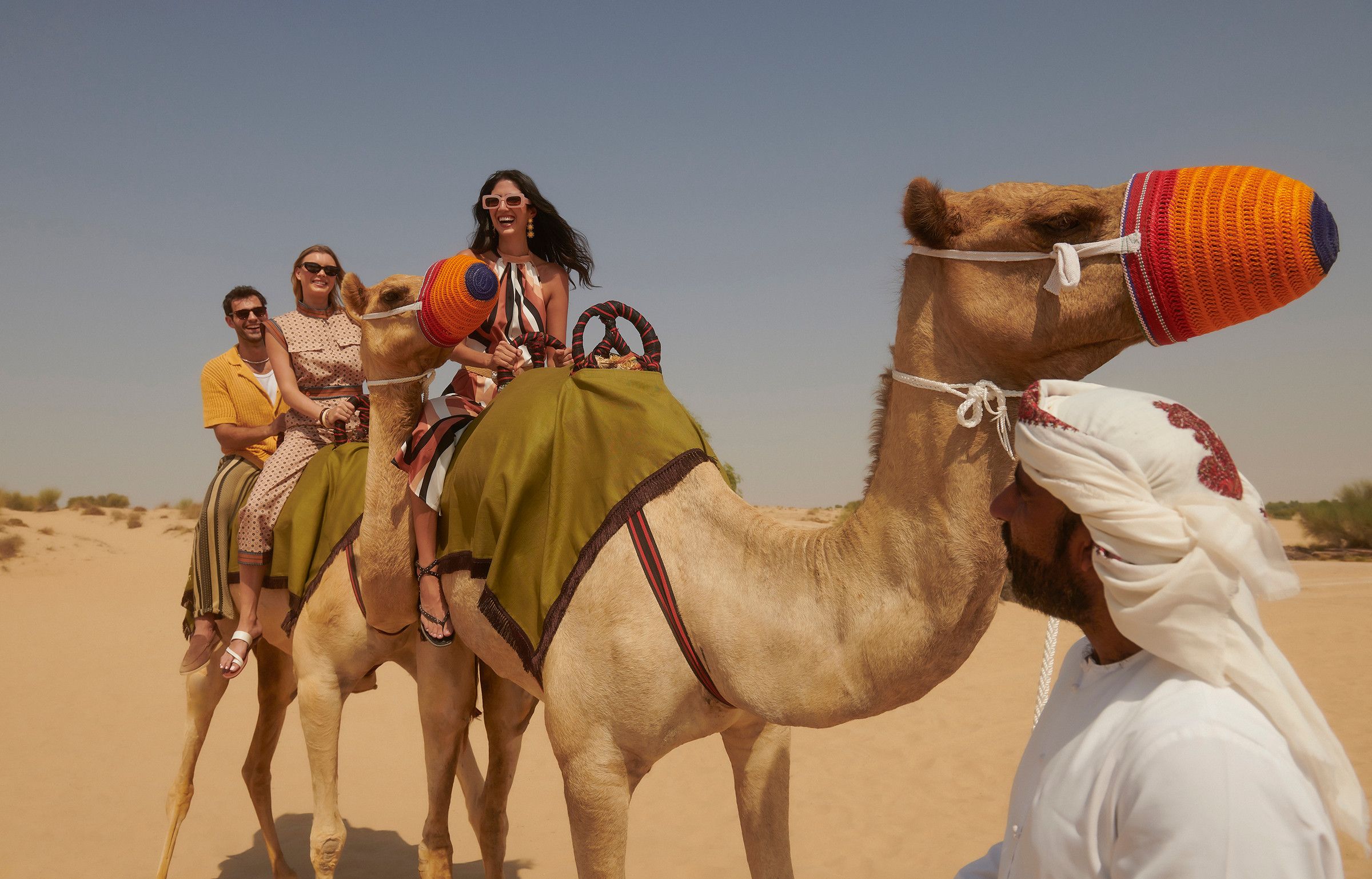 Travelers on a camel ride across the sand, led by a guide