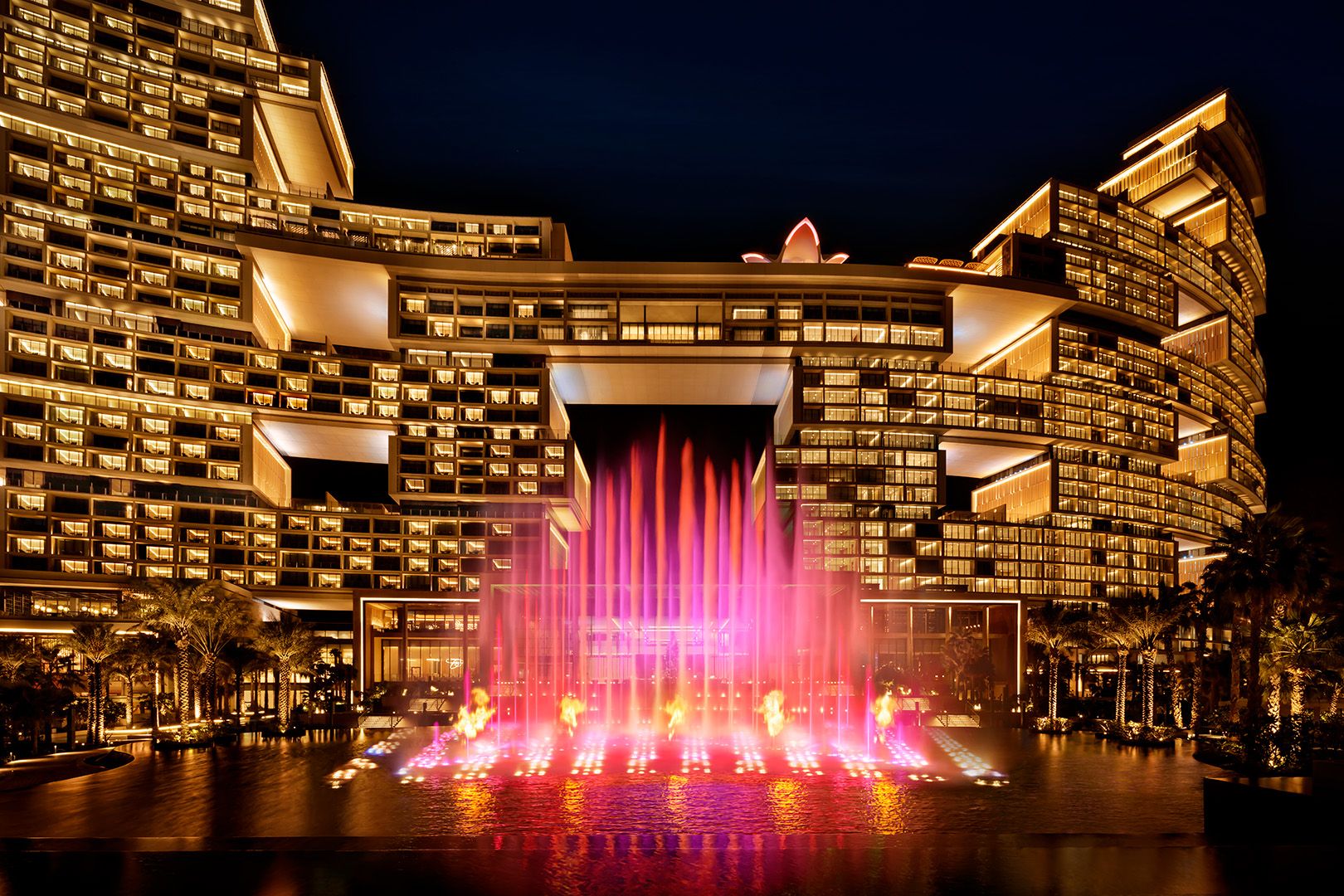 The Skyblaze fountain firing red and gold at night in front of Atlantis The Royal