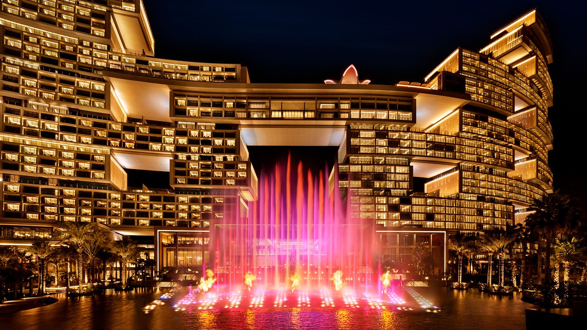 The Skyblaze fountain firing red and gold at night in front of Atlantis The Royal
