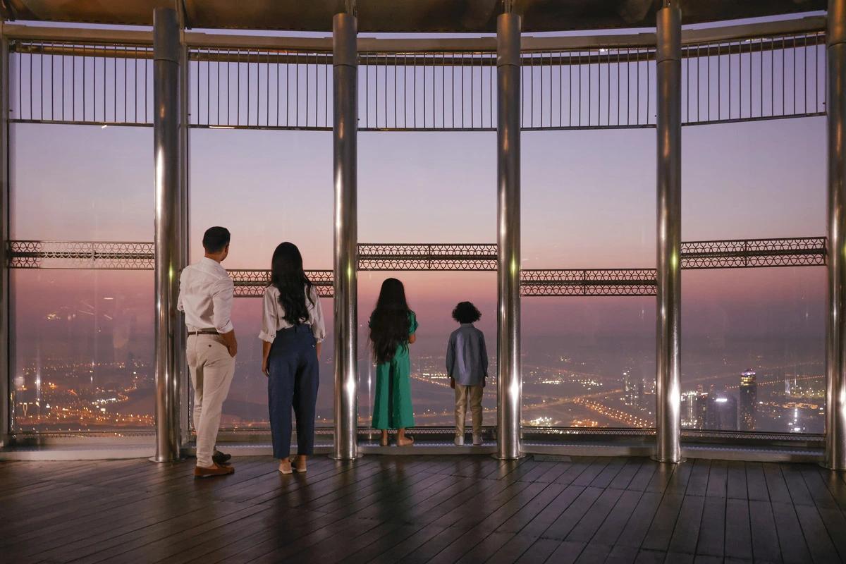 A family looking out over Dubai at dusk from the At the Top observation deck in Burj Khalifa