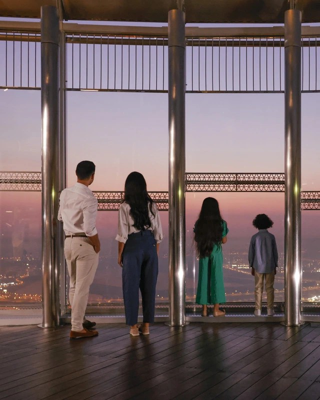 A family looking out over Dubai at dusk from the At the Top observation deck in Burj Khalifa