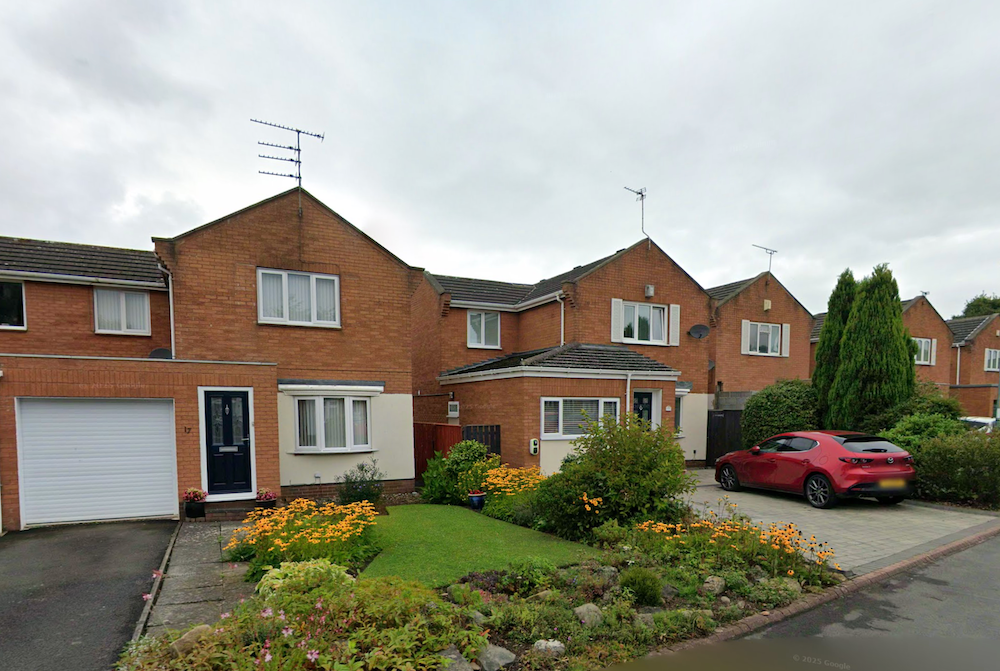 Modern detached brick houses with garages and a landscaped rockery garden on a 1980s cul-de-sac