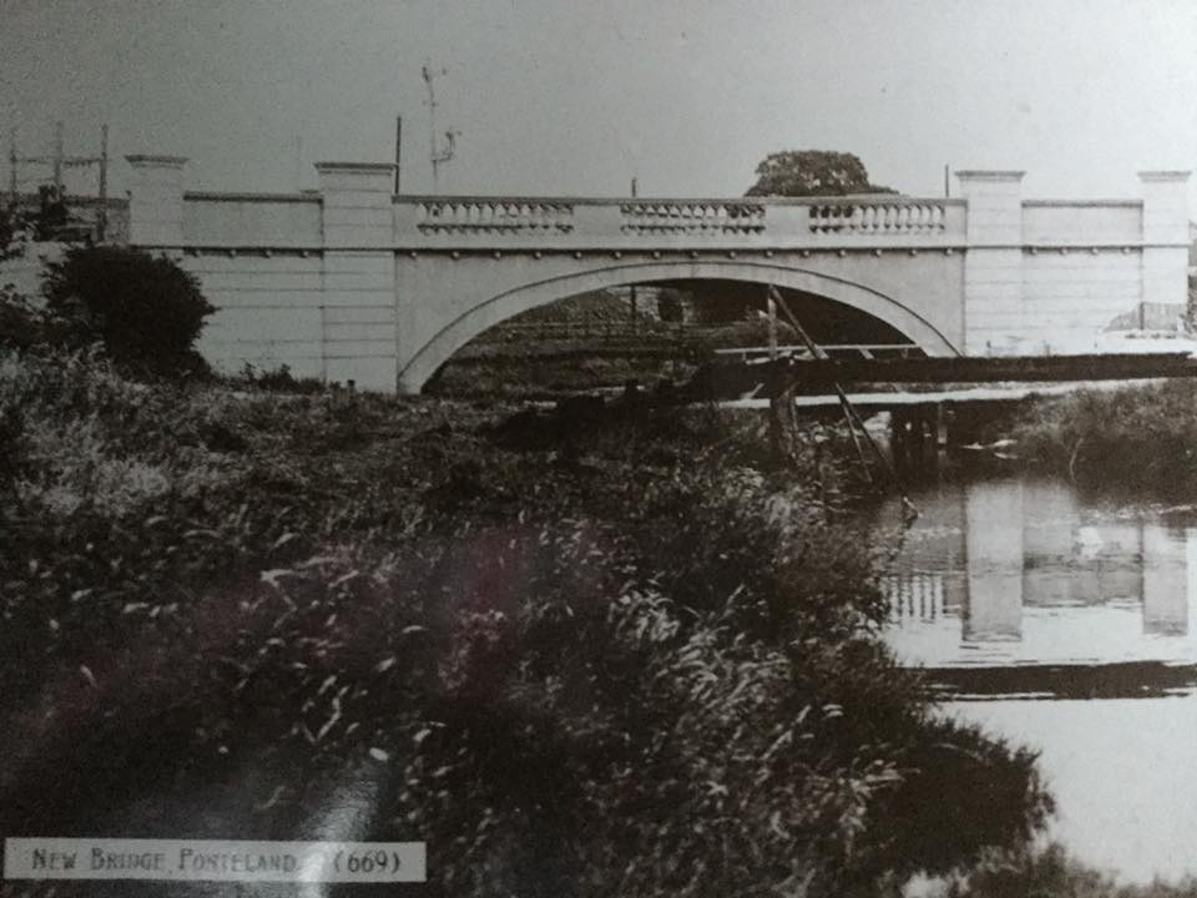 Black and white photograph of a balustraded concrete road bridge over a river, captioned New Bridge, Ponteland