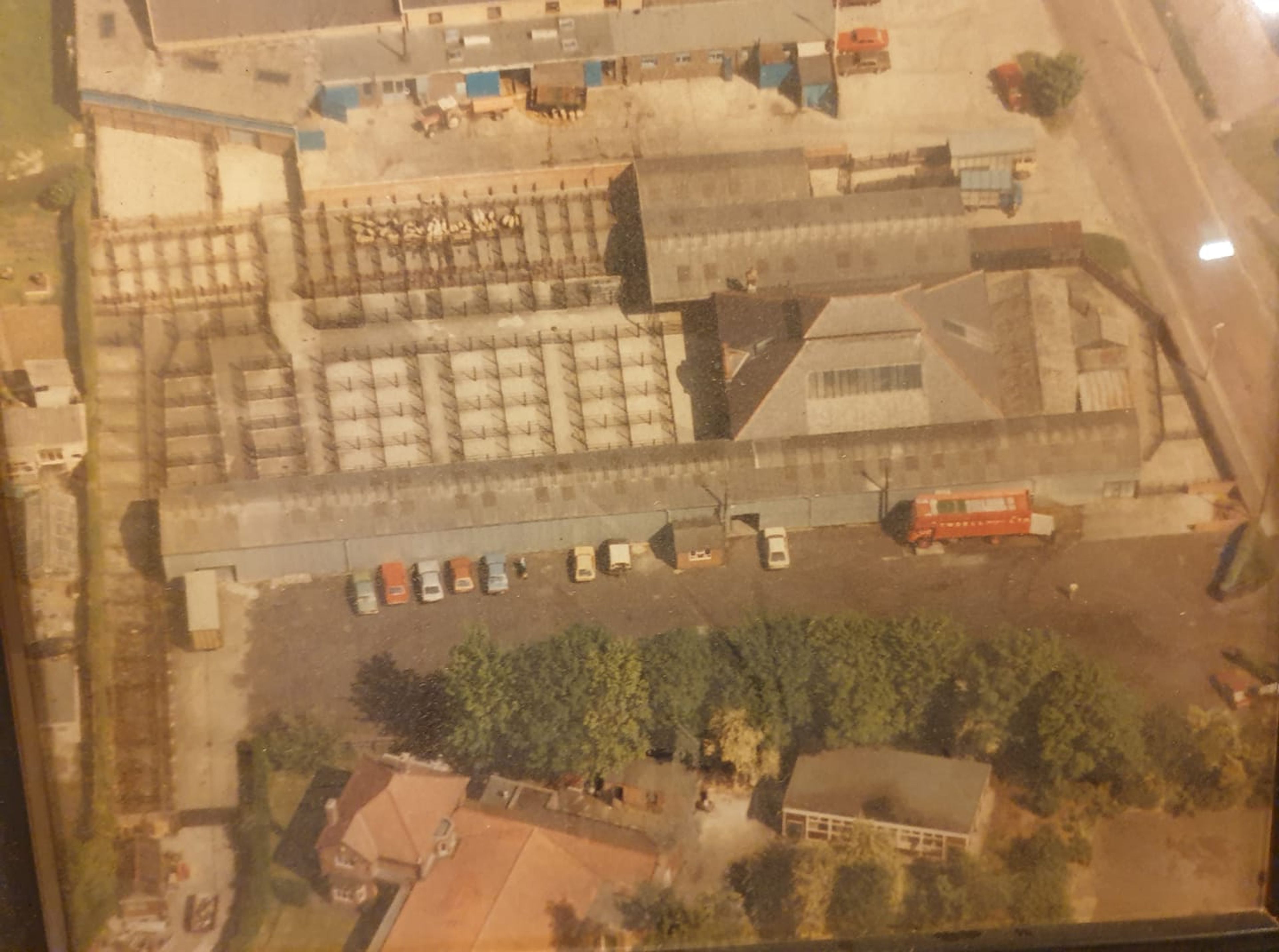 Aerial photograph of an auction mart with long roofed sheds and pens, cars parked alongside and a lorry in the yard