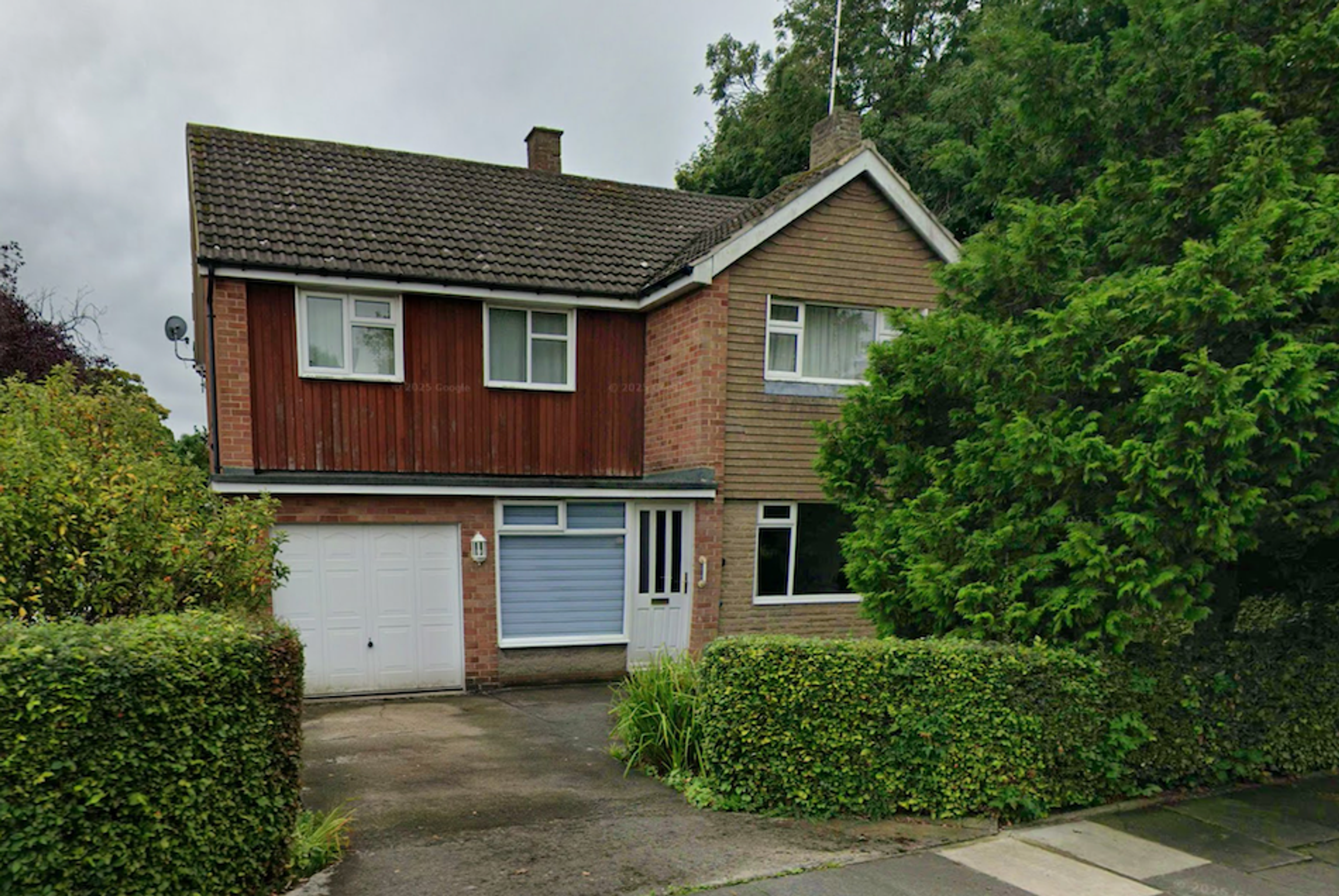 A 1960s detached house with timber cladding, an integral garage and a hedge along the front boundary