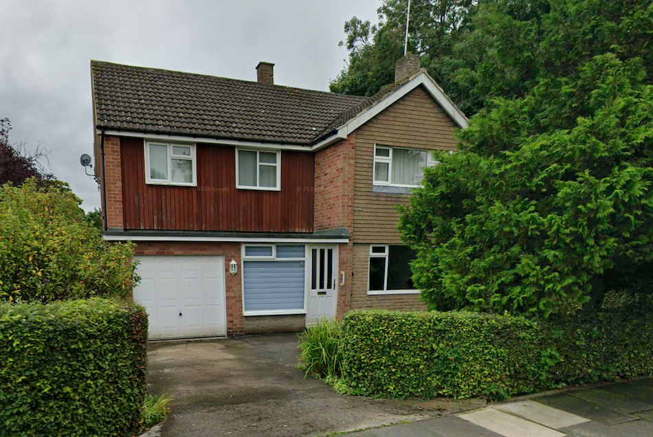 A 1960s detached house with timber cladding, an integral garage and a hedge along the front boundary