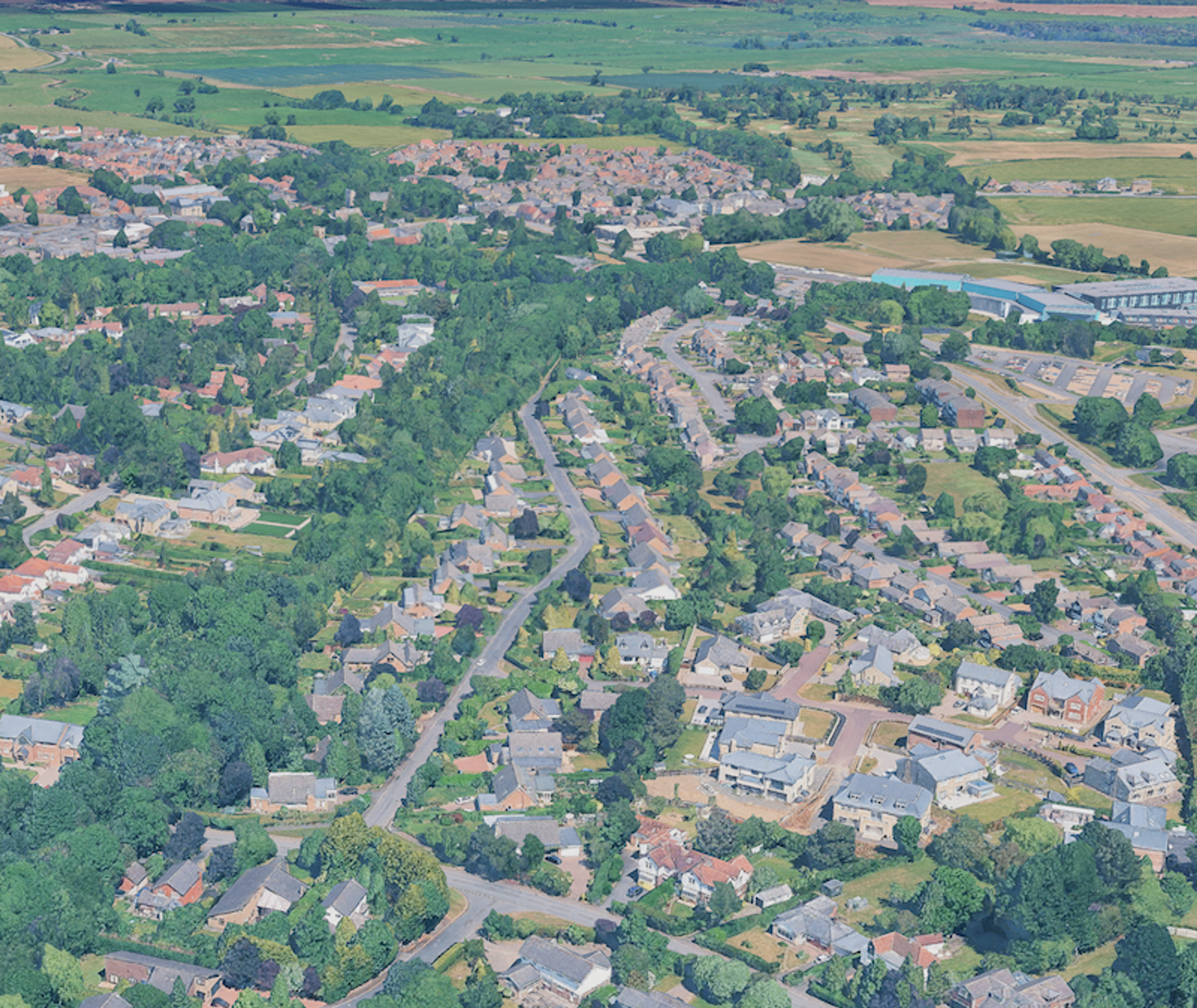 Aerial view of a large suburban estate of houses and bungalows on winding roads, with farmland beyond