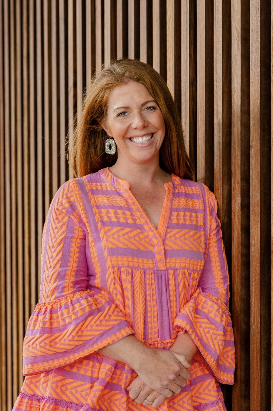 Kimberly smiling in front of a timber wall