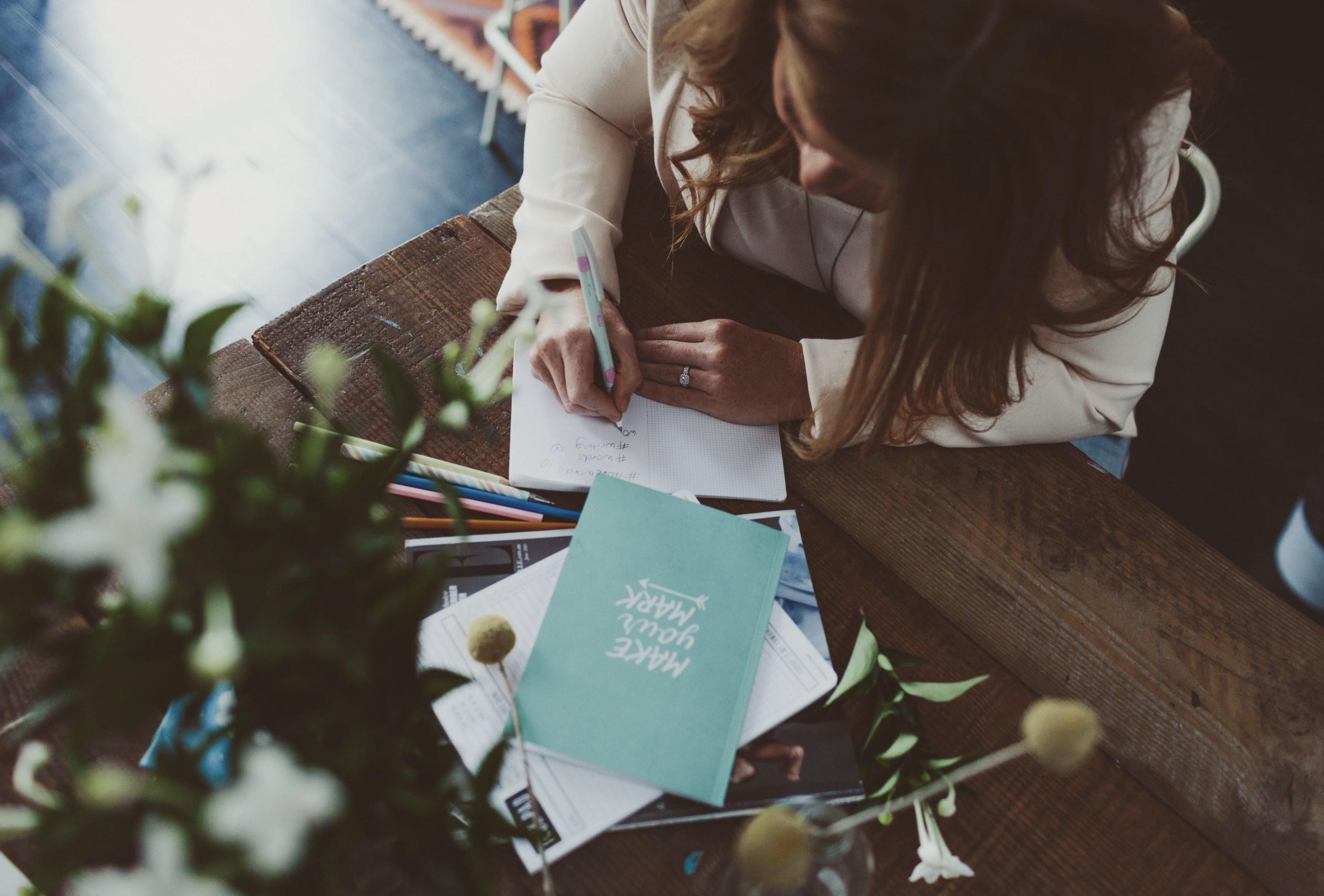 Writing in a notebook surrounded by stationery