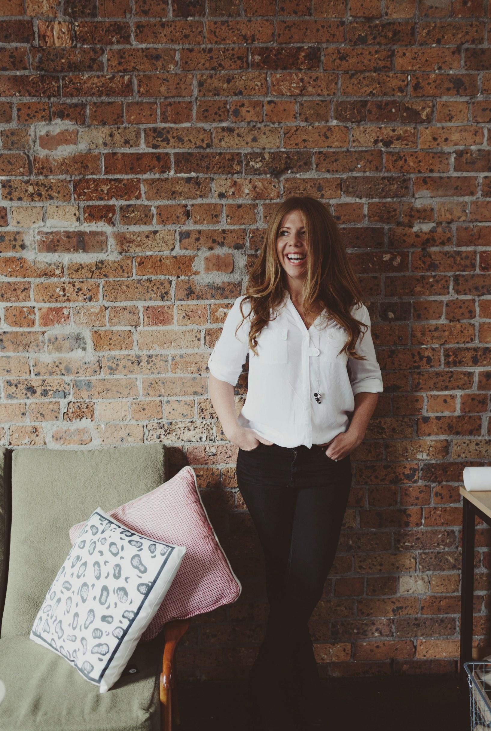 Kimberly leaning against a brick wall