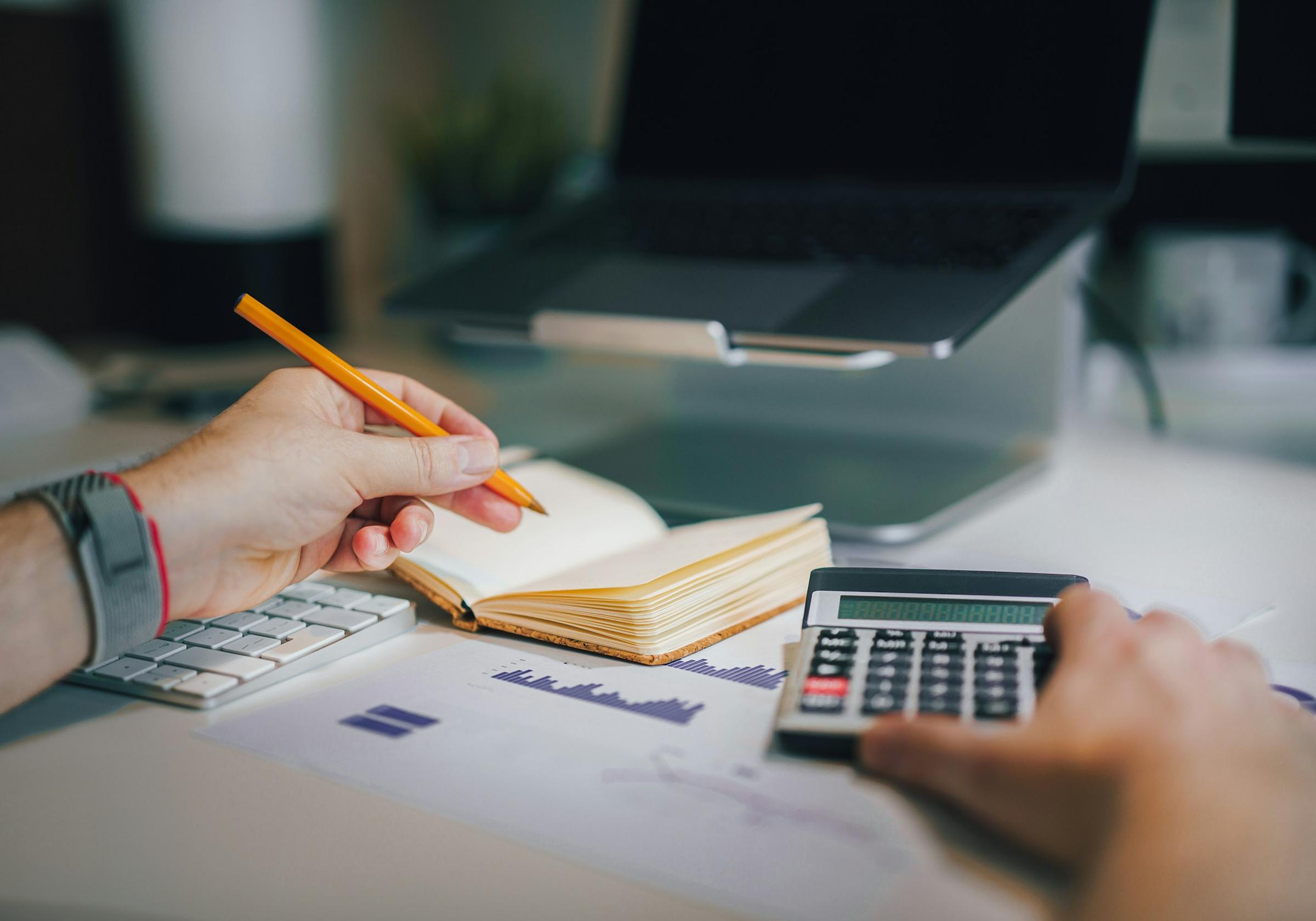 Hands working out a budget with a calculator and notebook