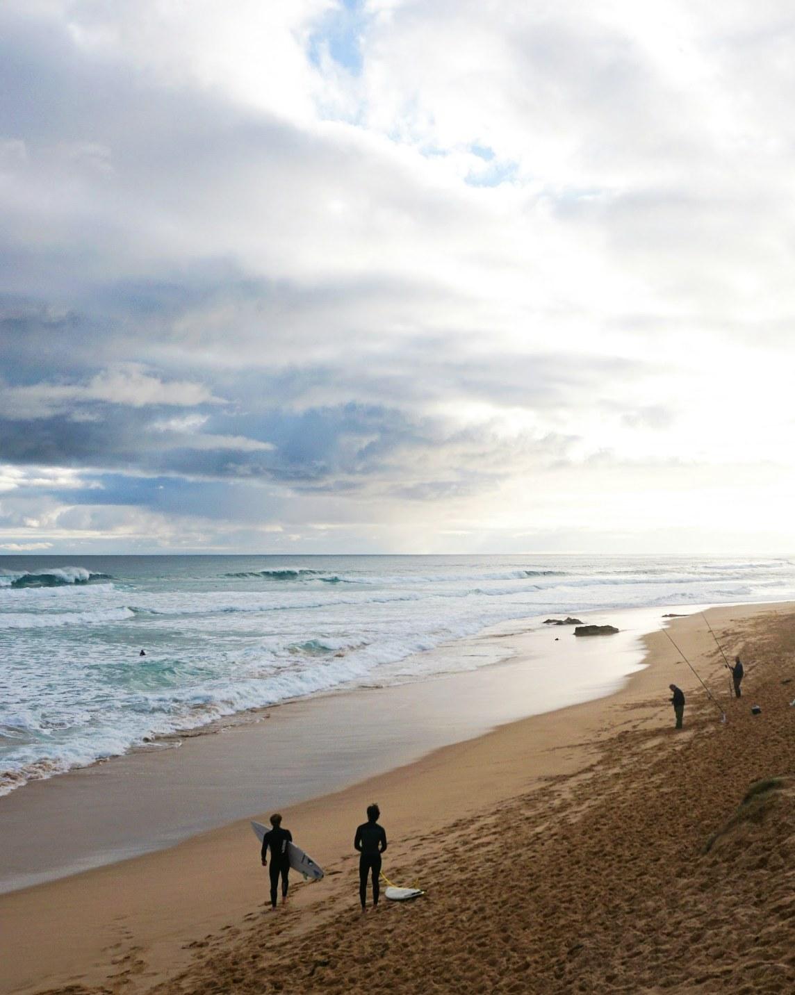 Surfers walking along the beach