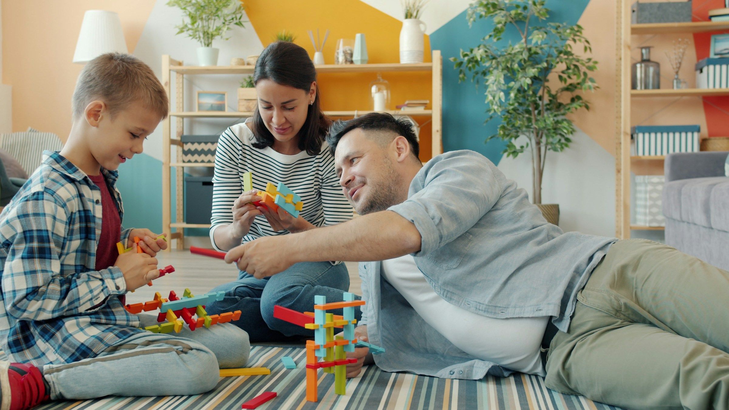 A family building with colourful toy blocks on the floor at home