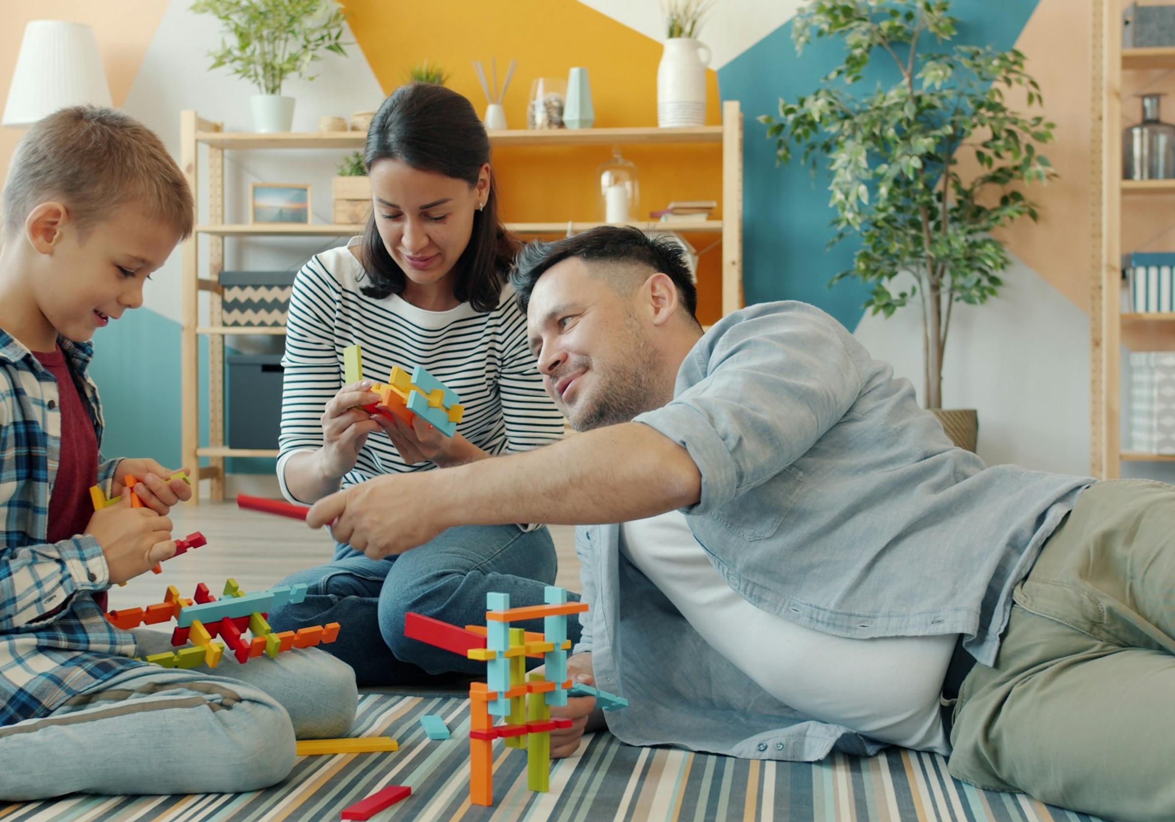 A family building with colourful toy blocks on the floor at home