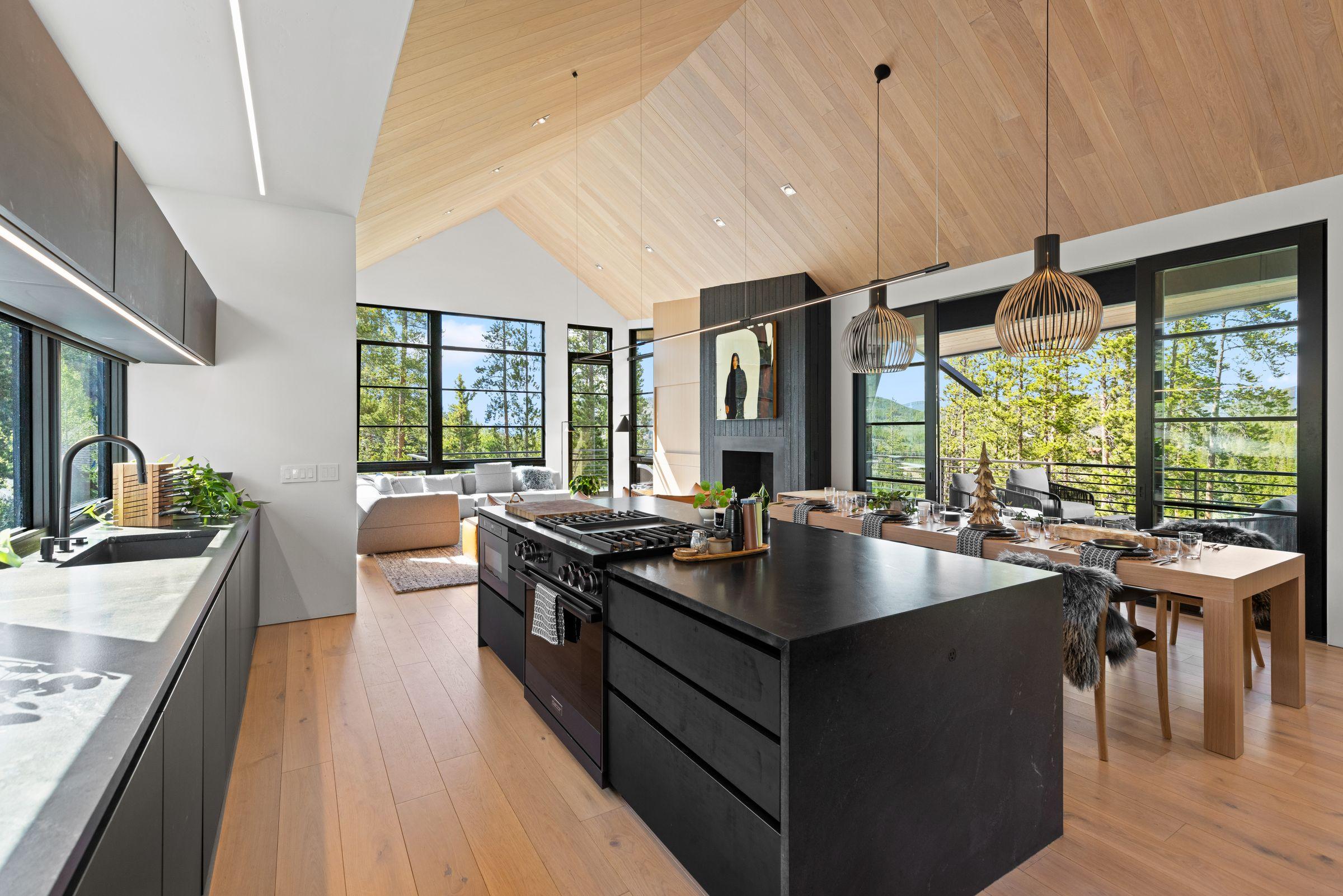 Kitchen in white oak with a black island, windows onto the trees