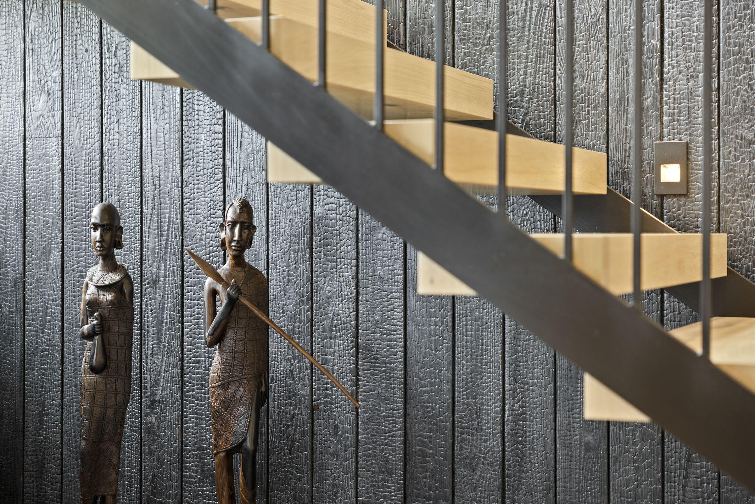 Charred vertical siding with a carved figure mounted against it