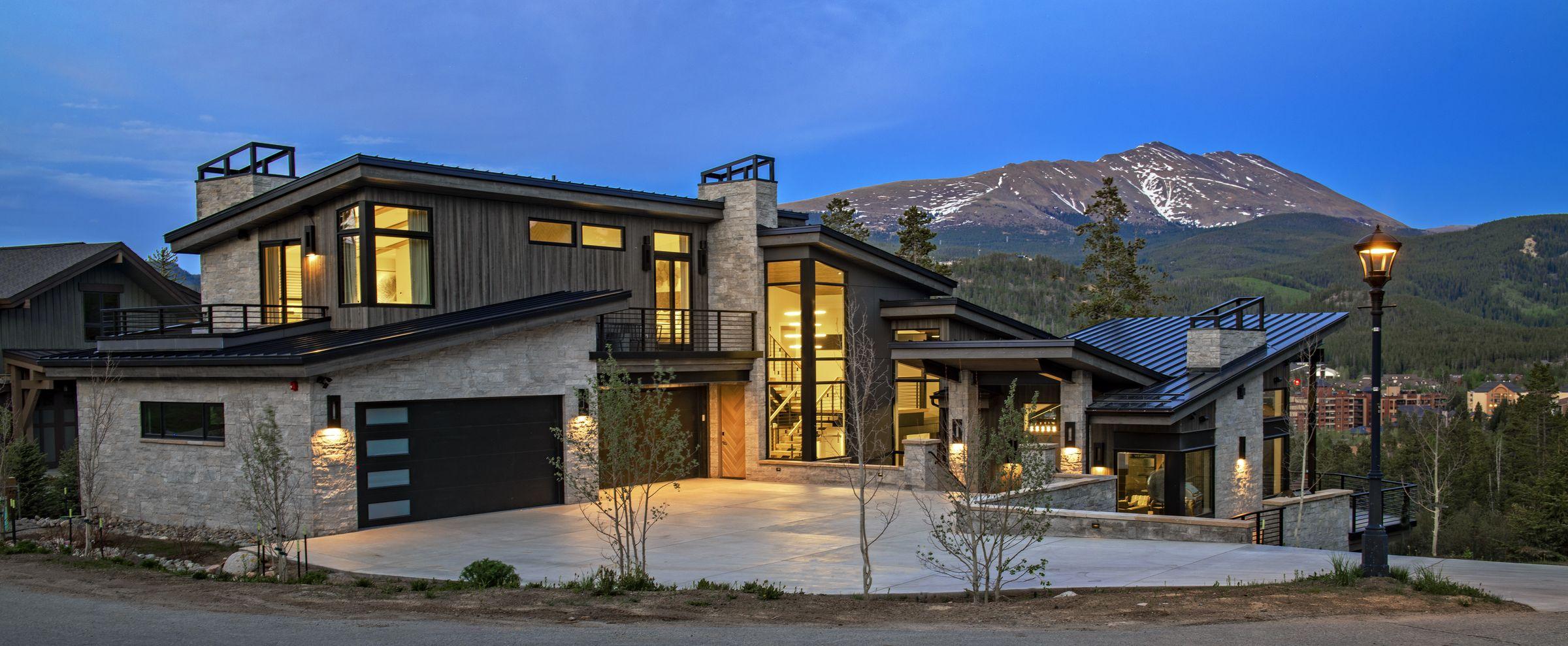 Exterior at dusk, lit windows and the peaks behind