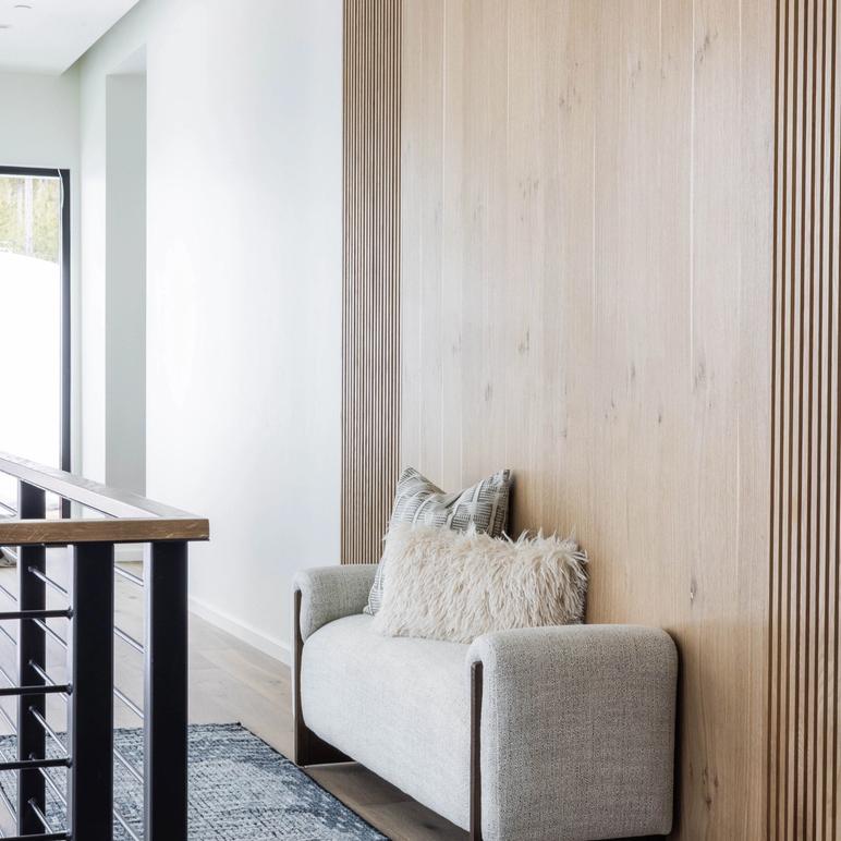 Upstairs landing with a small bouclé loveseat against a white-oak slat wall, a patterned runner and a black steel railing