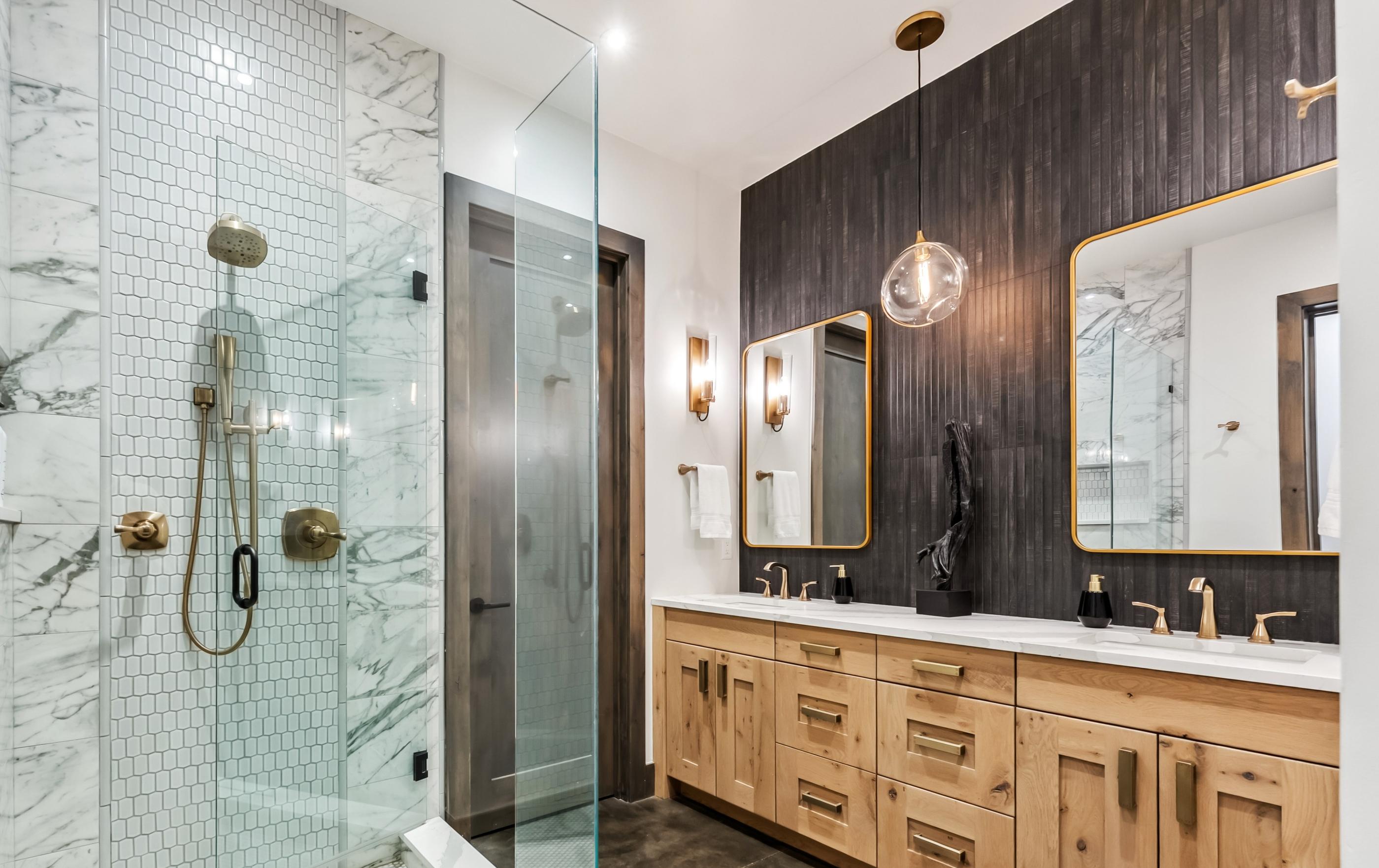 Renovated primary bathroom with a marble shower, timber wall and brass fittings