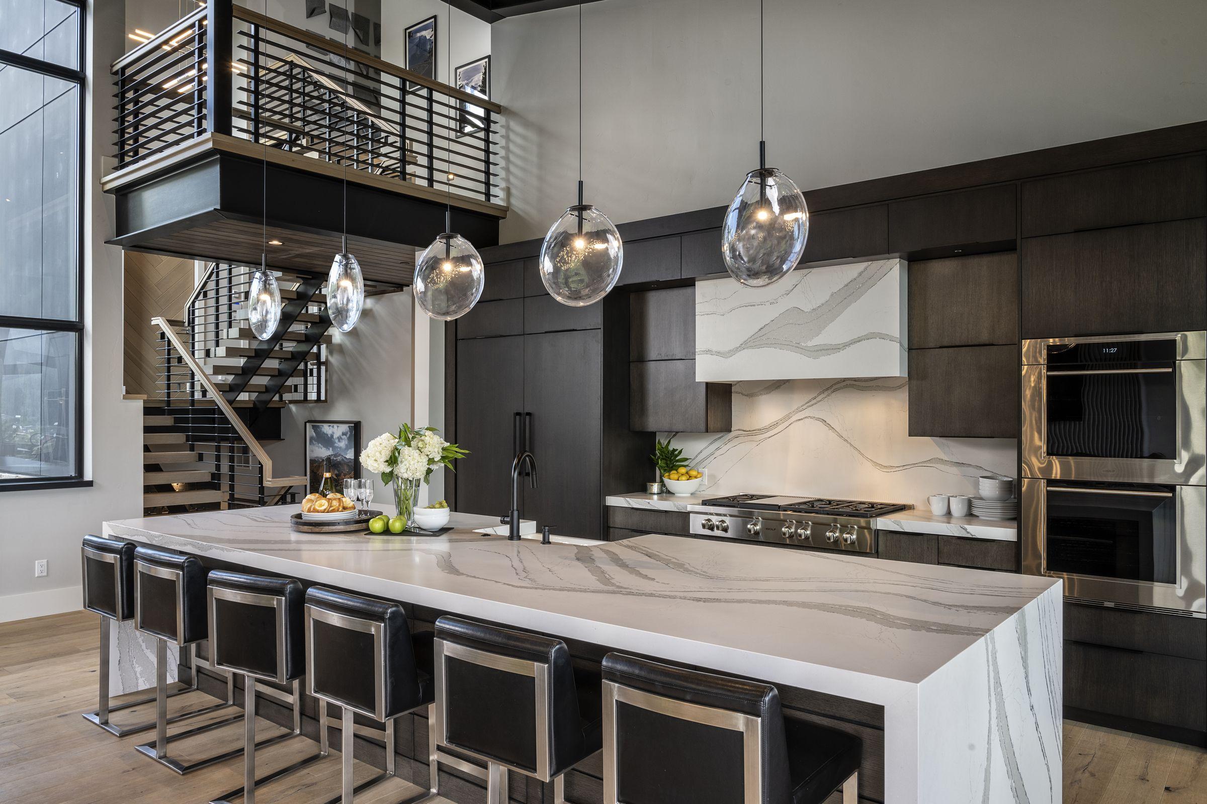 Kitchen and great room with a blackened steel railing and pendant lights over the island