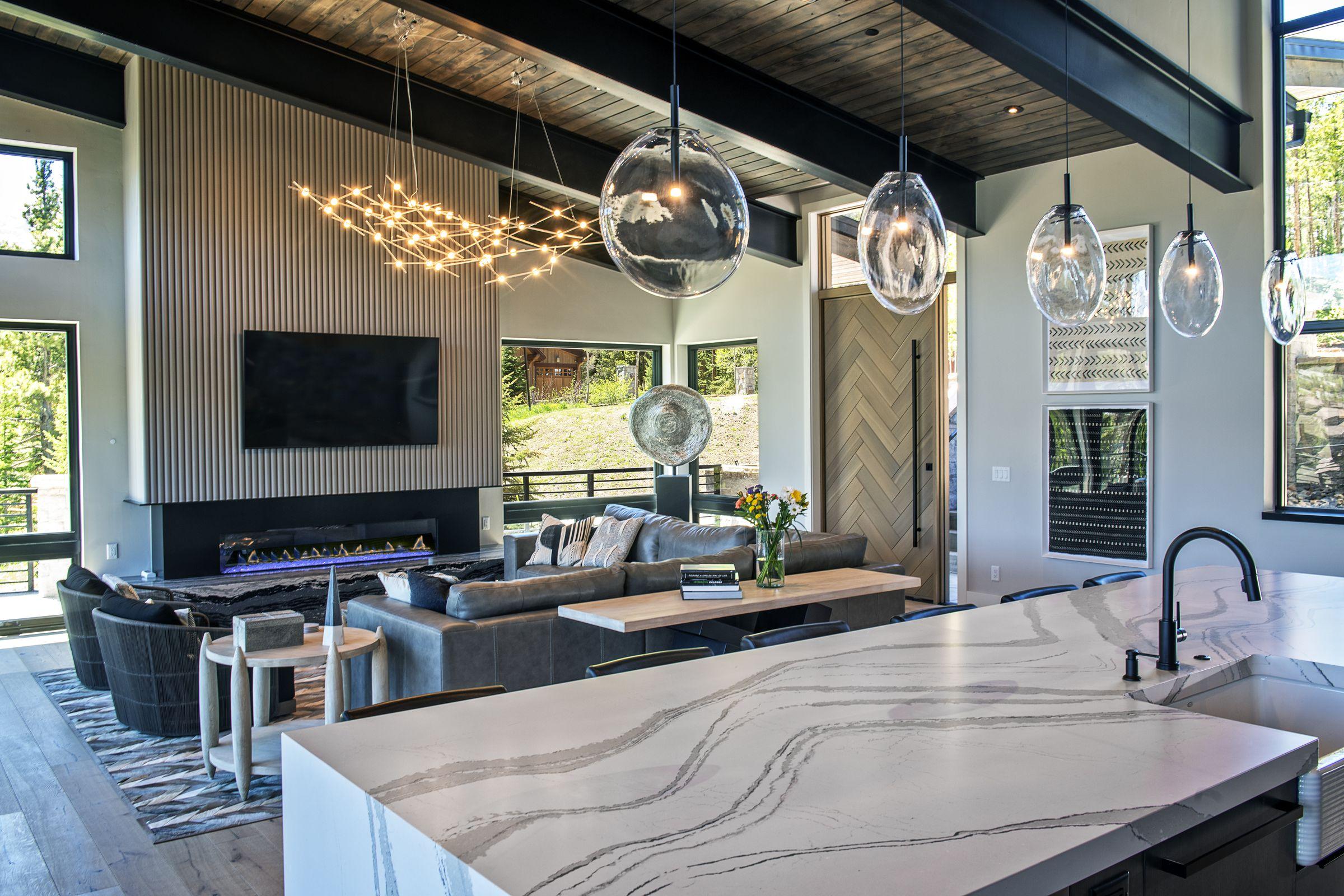Kitchen with a marble island, dark cabinetry and a linear chandelier