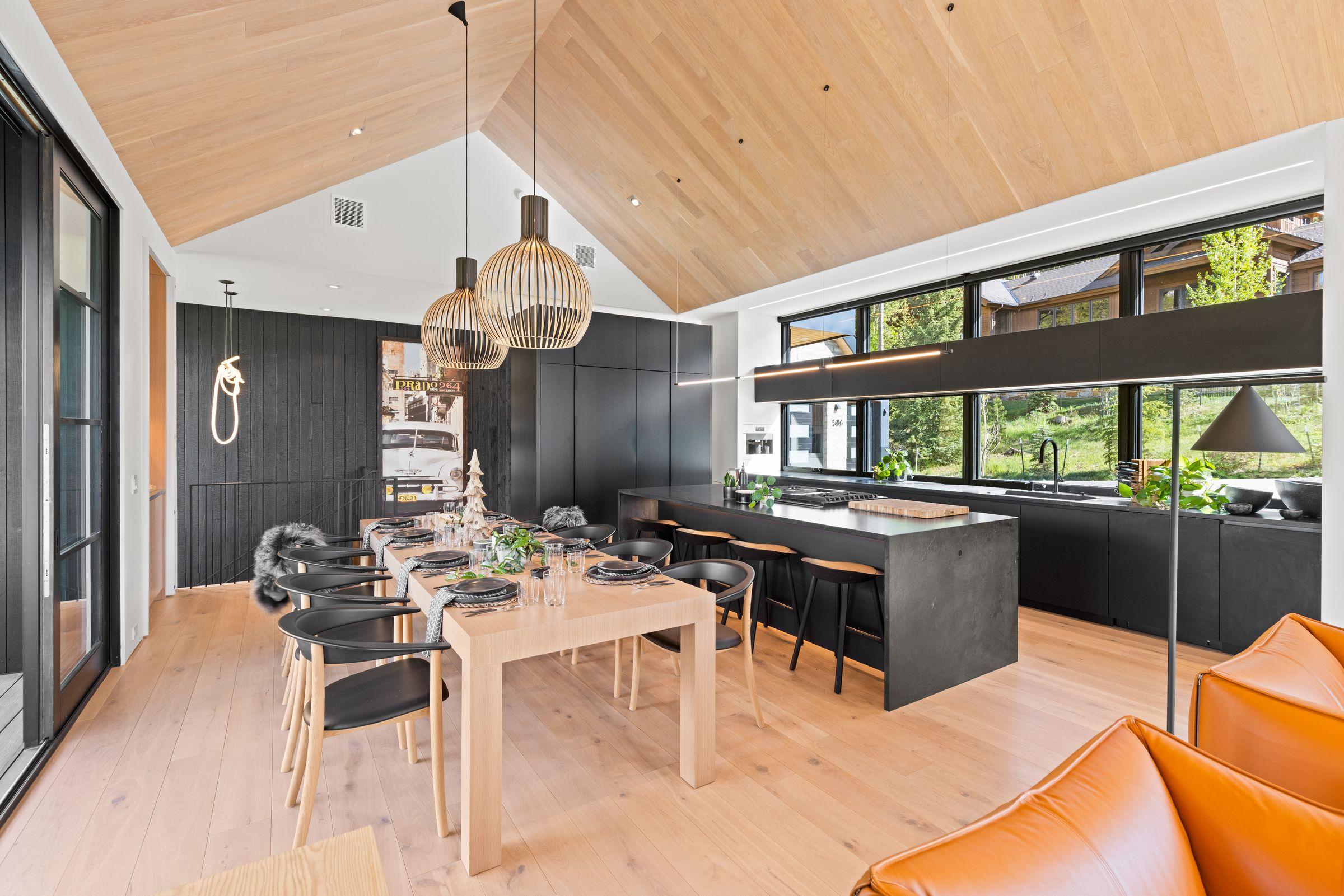 Open kitchen and dining under oak ceilings, an orange sofa in the foreground