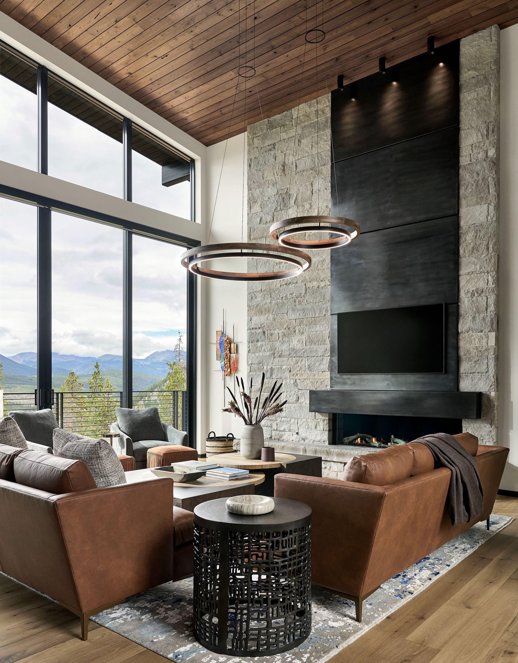 Great room with a full-height stone fireplace, ring chandeliers and leather seating
