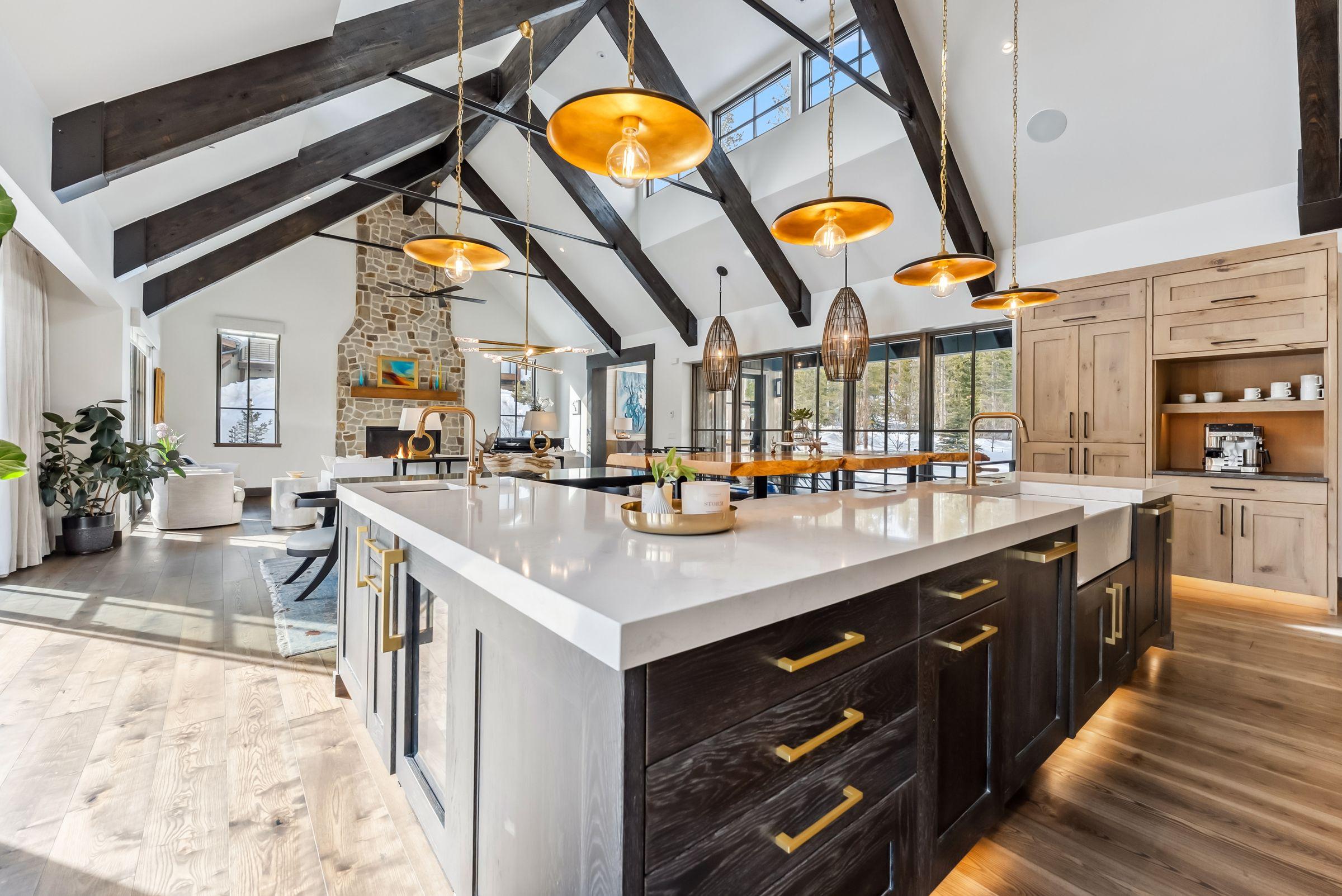 Kitchen with dark cabinetry, brass fittings and a marble island under the trusses
