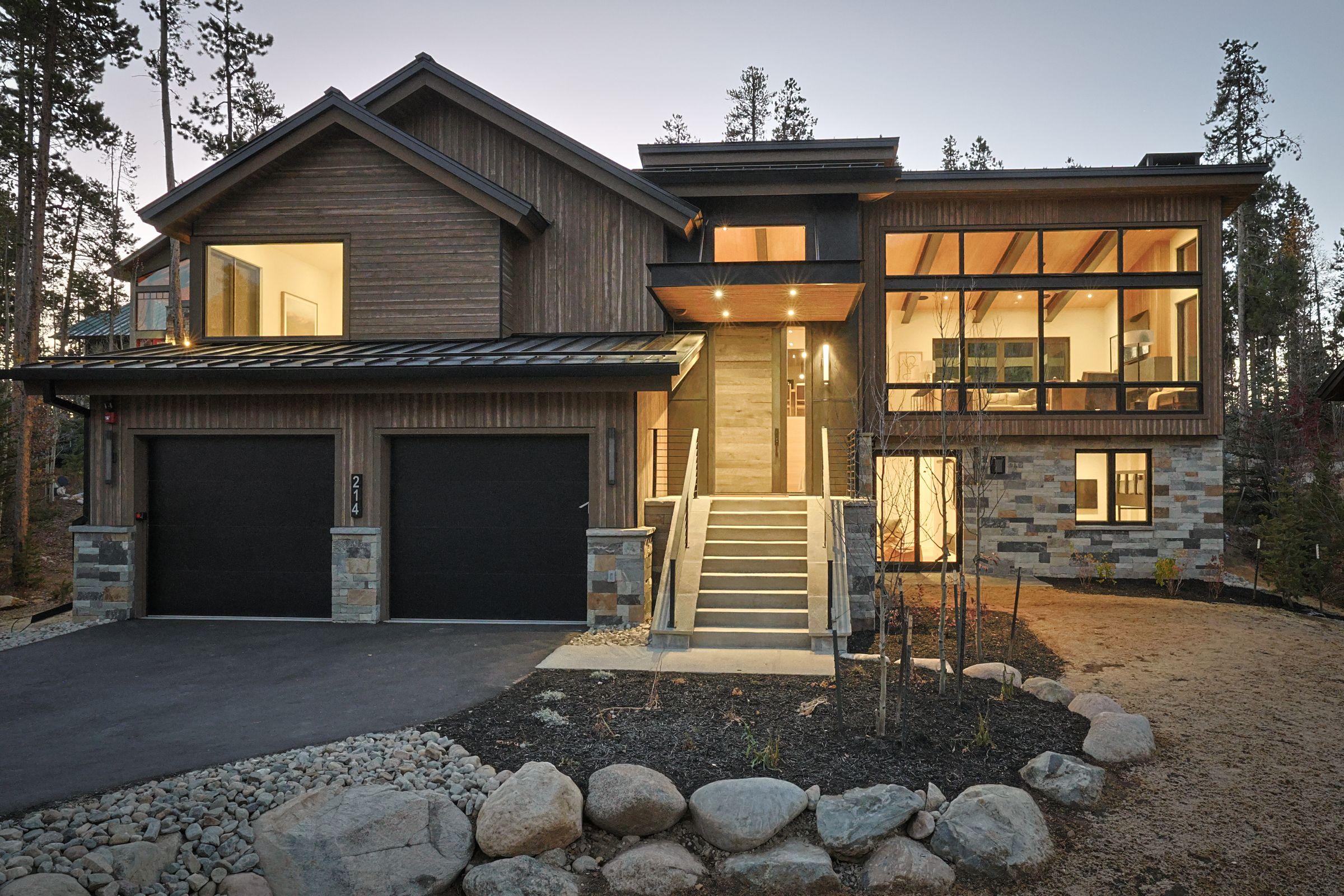 Exterior in timber and stone, boulders set along the drive