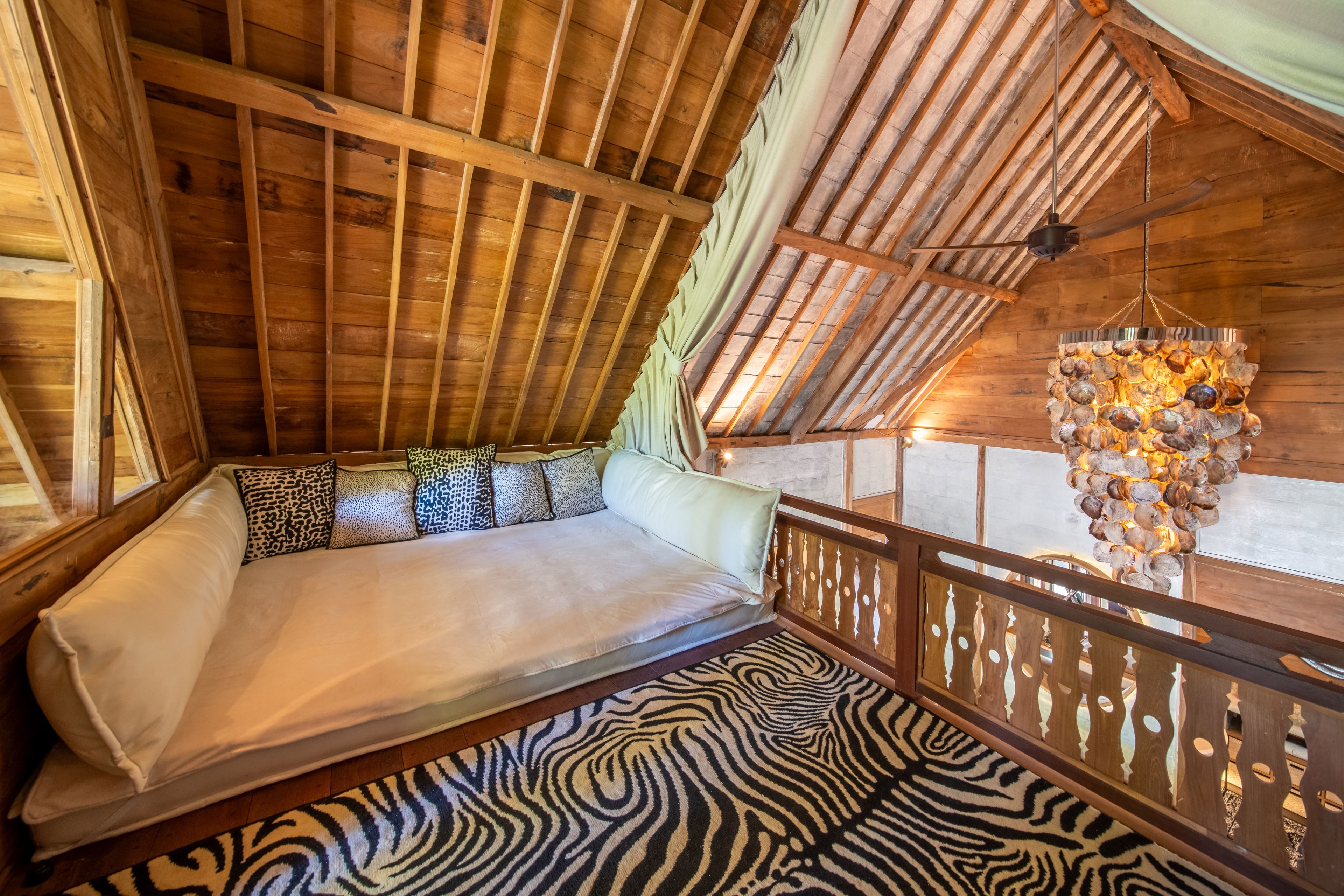 A built-in daybed with leopard cushions in the loft, above a zebra-striped rug.
