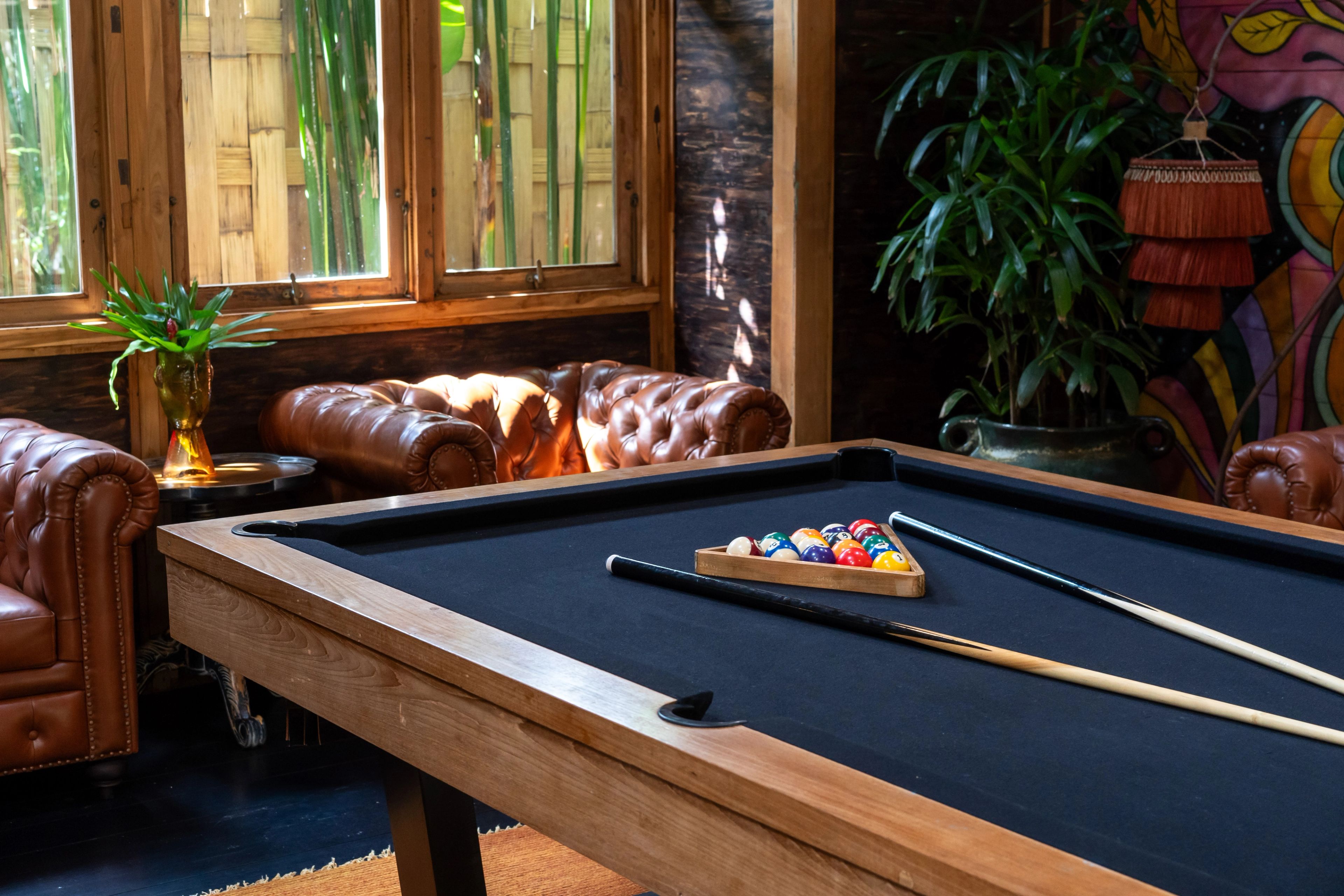 Racked balls on the pool table with a tan chesterfield behind and the mural to one side.