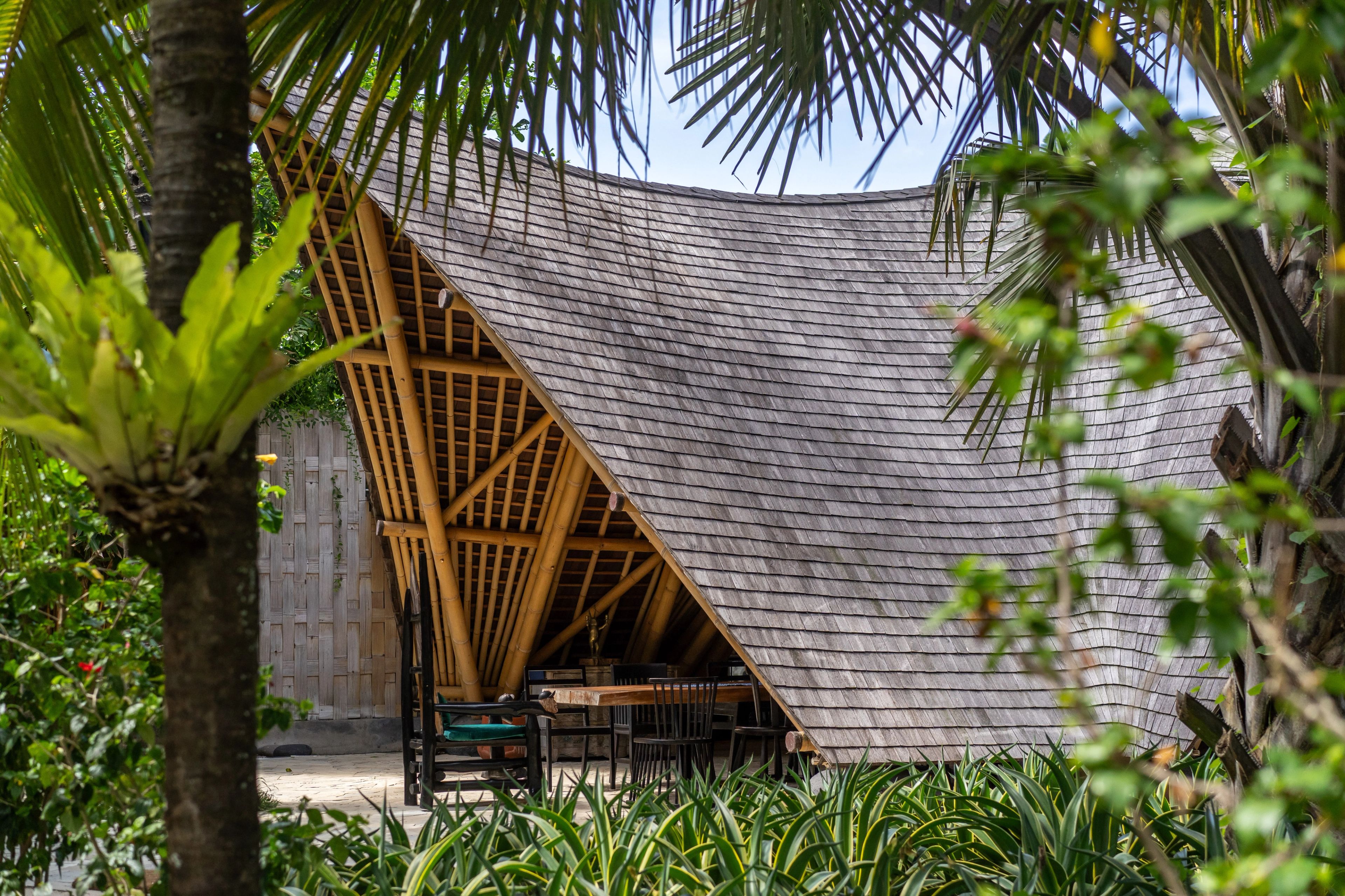 The steep shingled A-frame of the restaurant seen through the palms.