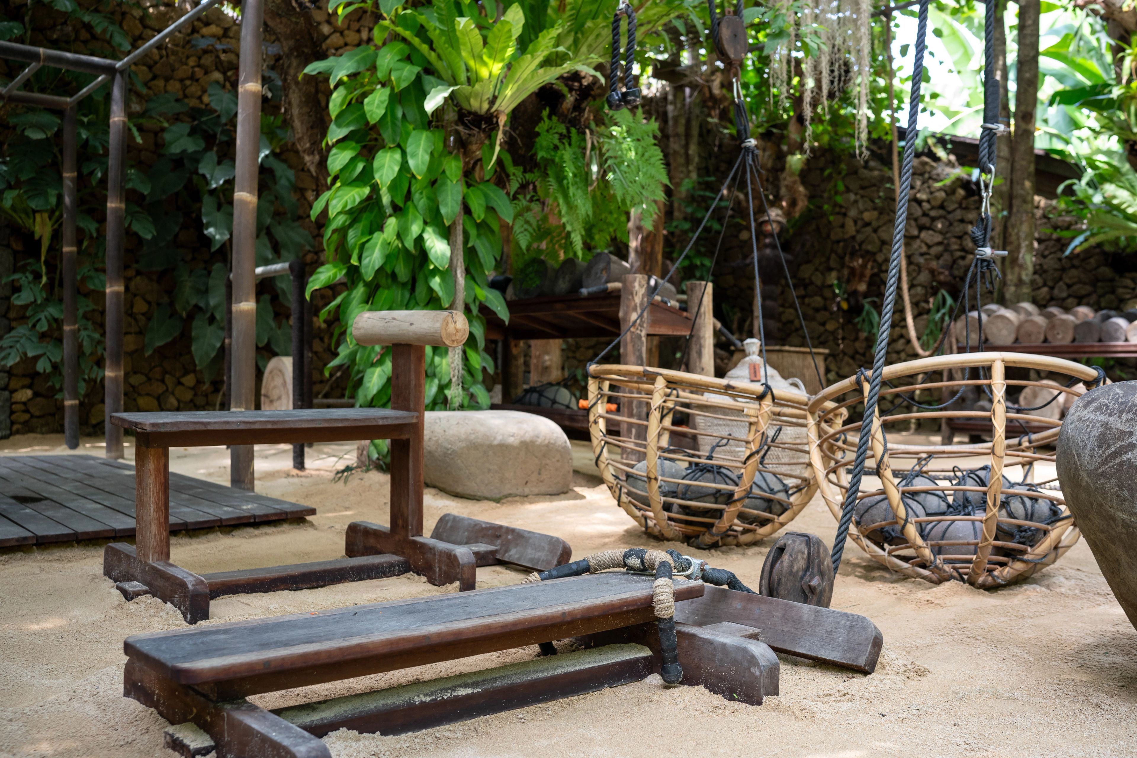Rattan baskets of stones hung on ropes beside benches on the gym's sand floor.