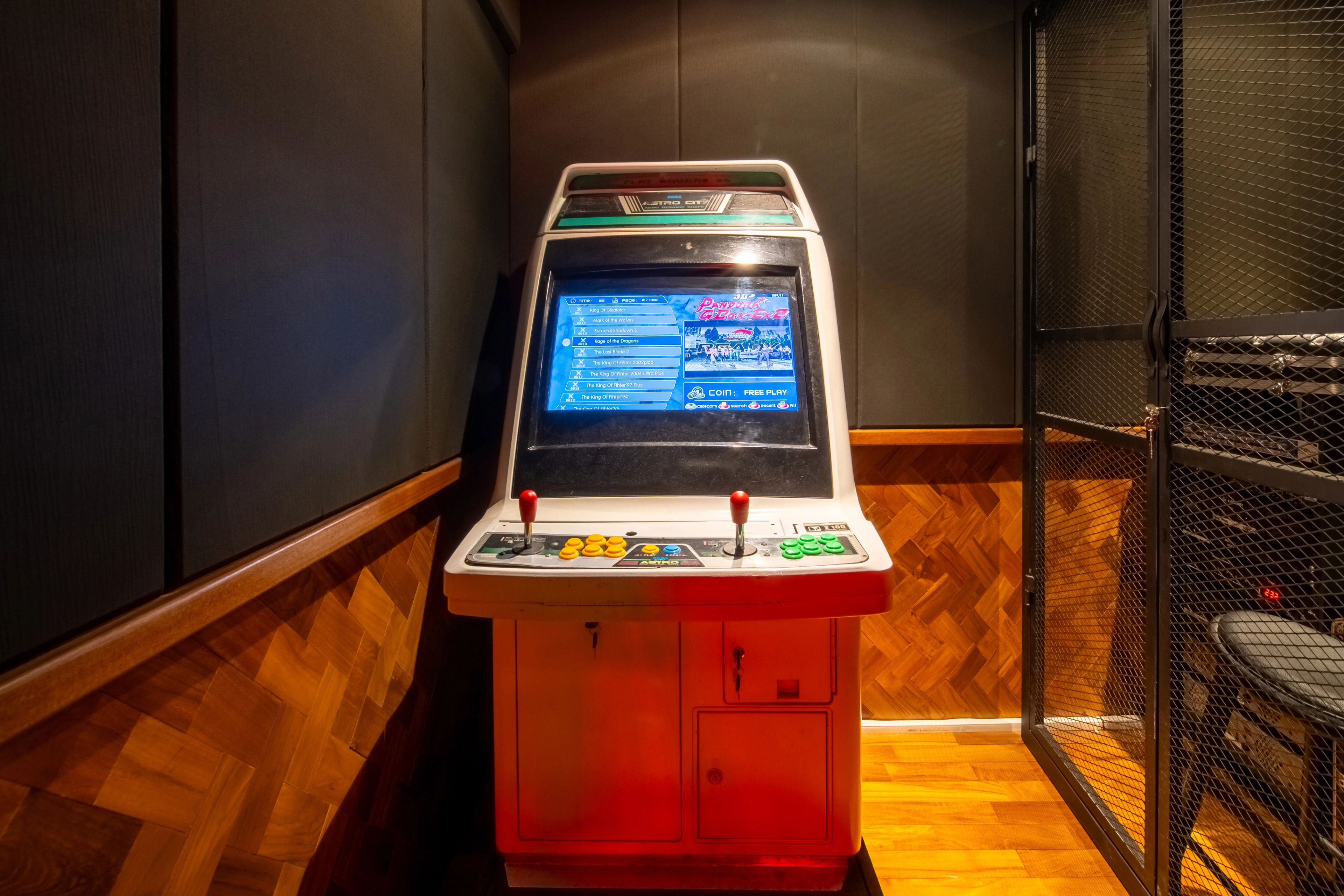 A red arcade cabinet standing against the timber panelling beside the booth seating.