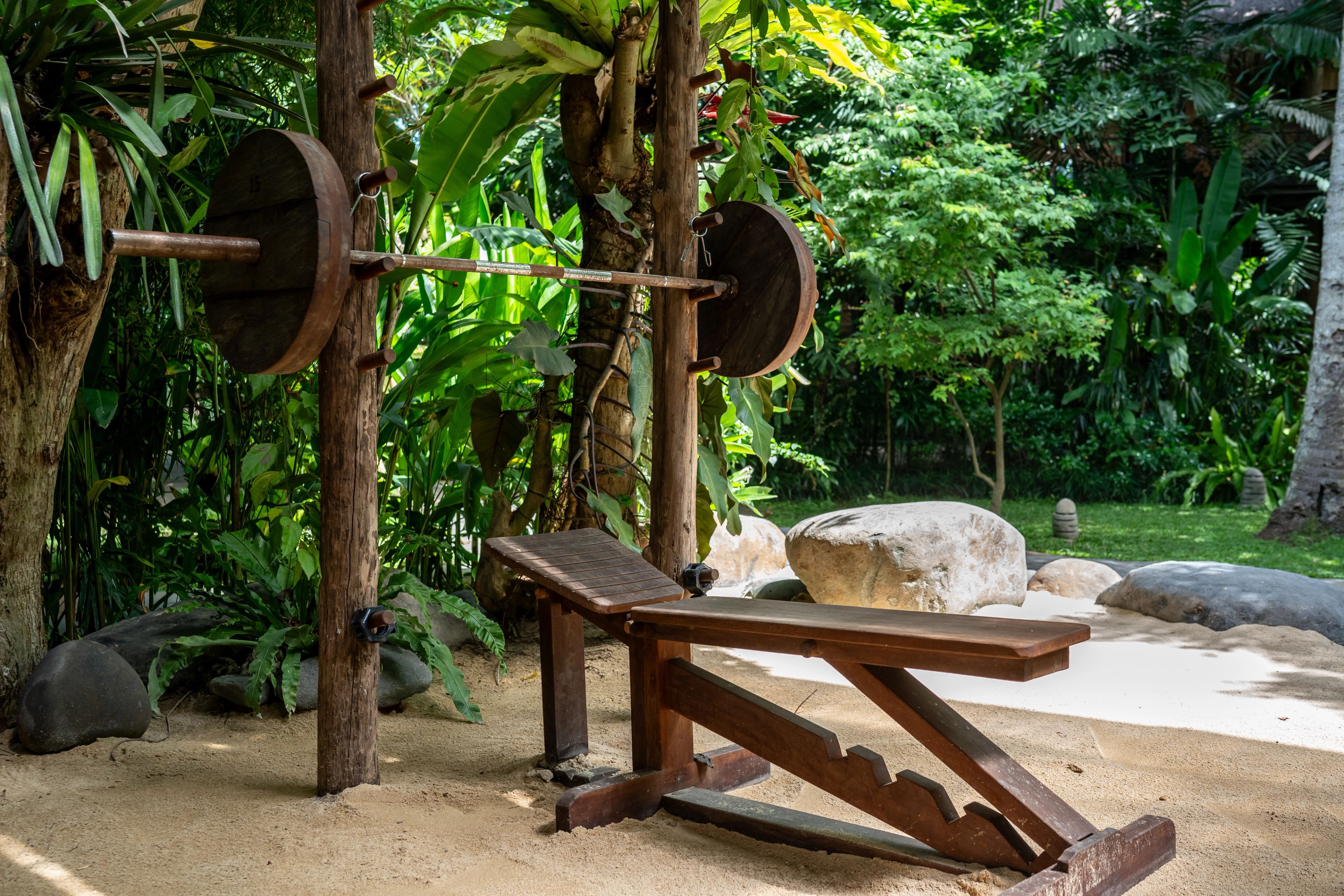 Wooden barbell and adjustable weight bench in the outdoor jungle gym.