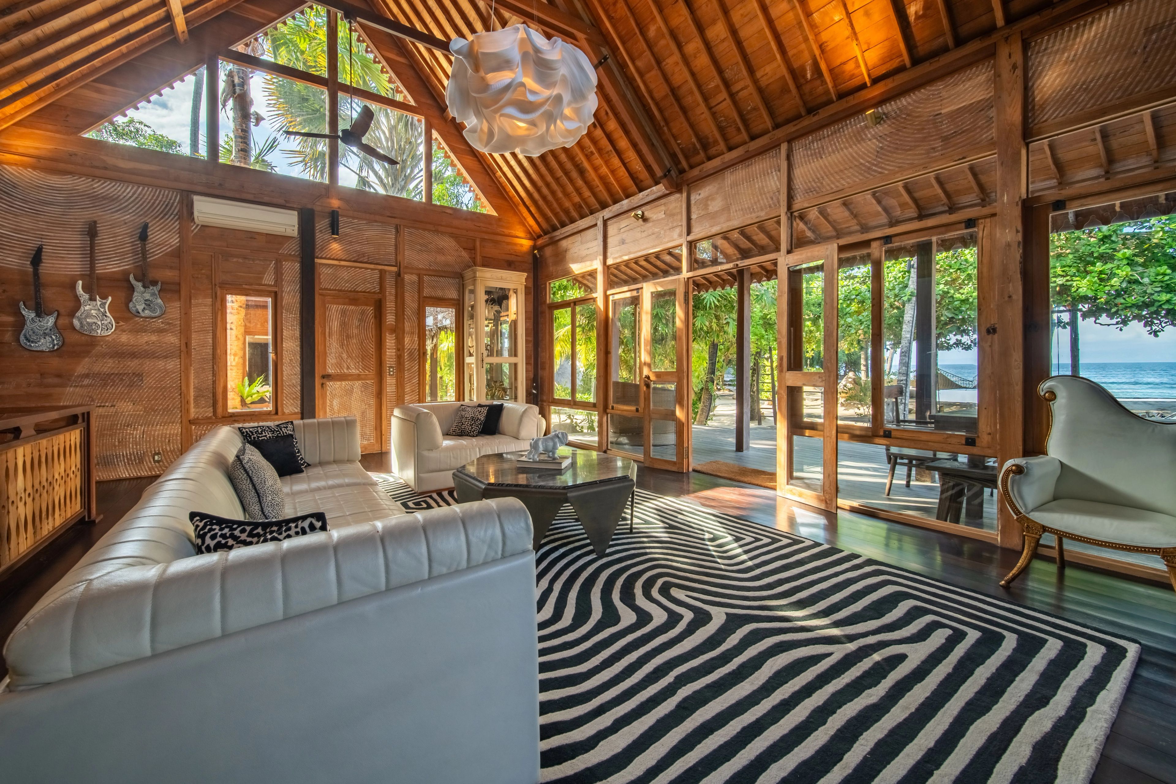 The sectional sofa along the windows on a striped rug, guitars mounted on the wall to the left.
